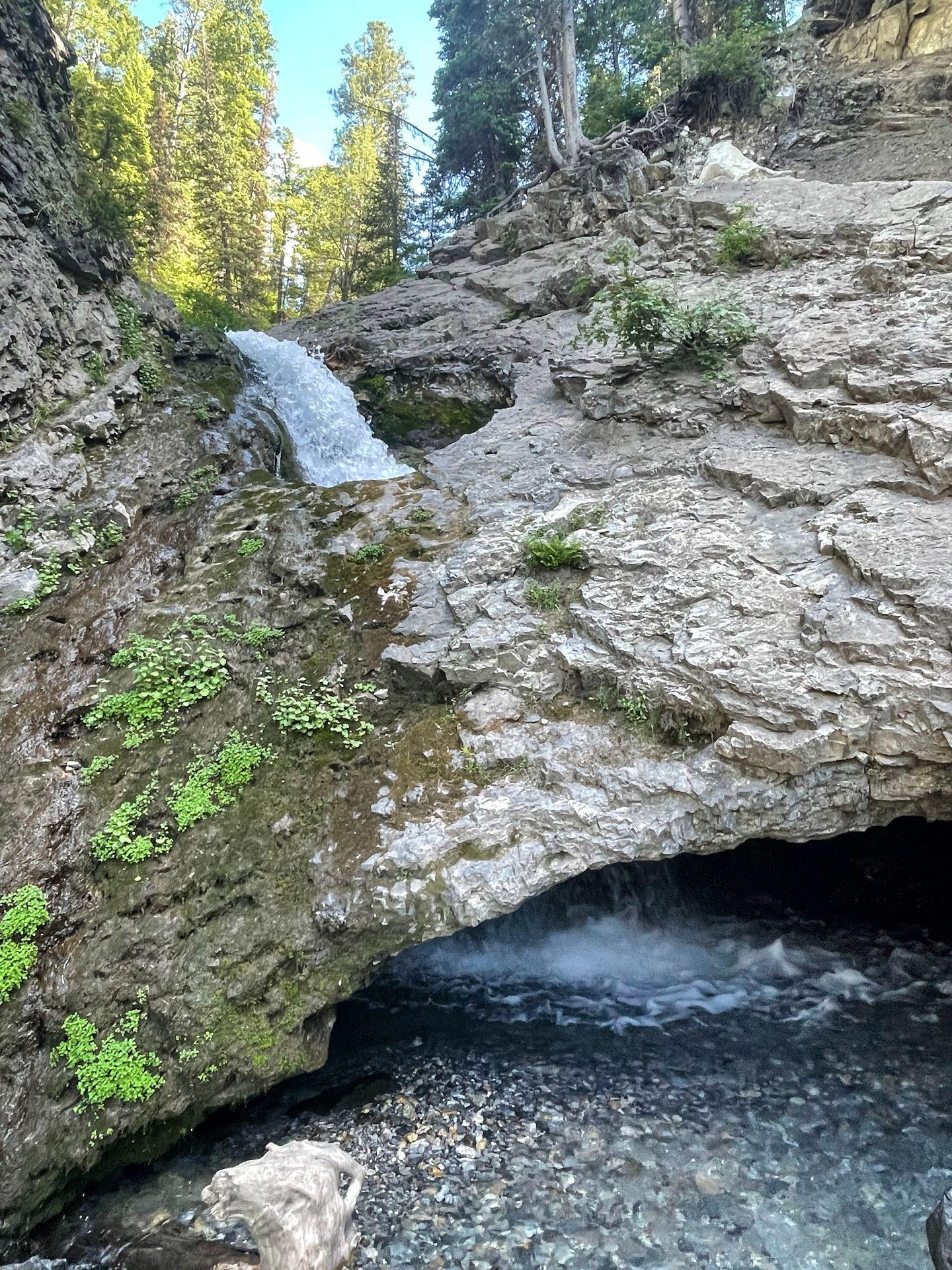 A waterfall flowing through a hole in the rocks at Donut Falls.