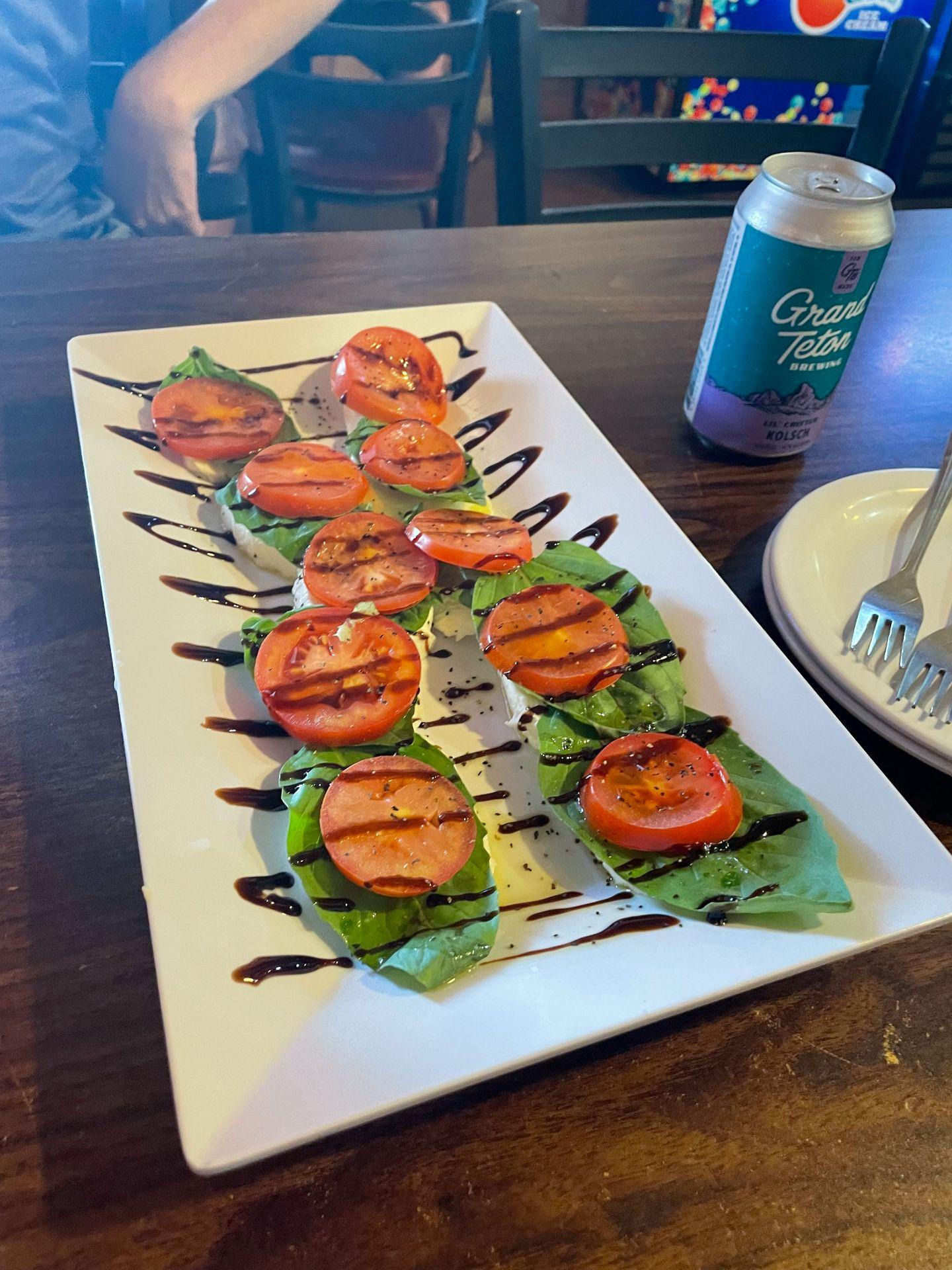 A plate of caprese from Papa Brunee's. There are 10 sections of mozzarella topped with basil, tomatoes and balsamic.
