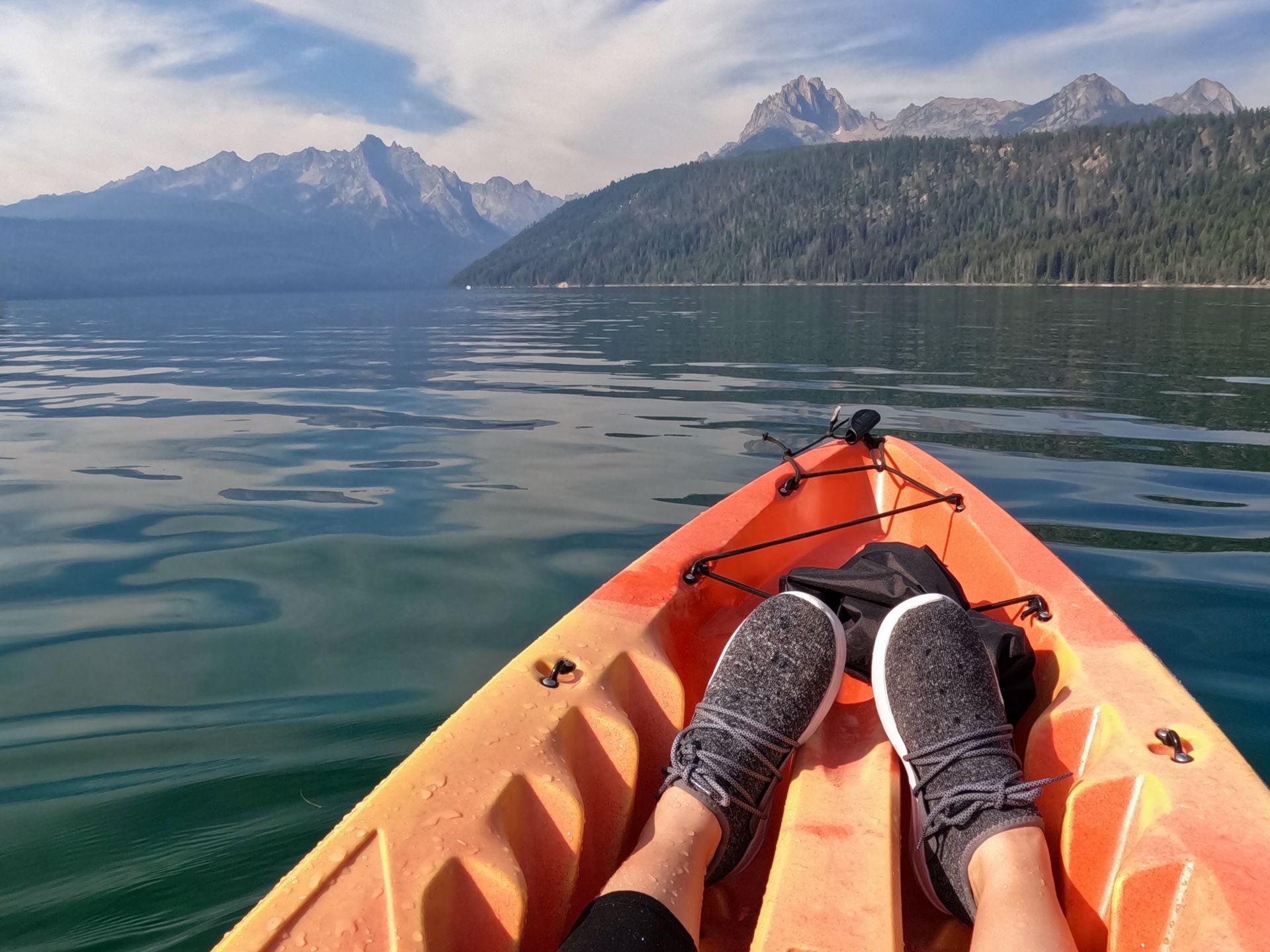 Kayaking on Redfish Lake. The water is surrounded by trees and there are mountains in the distance.