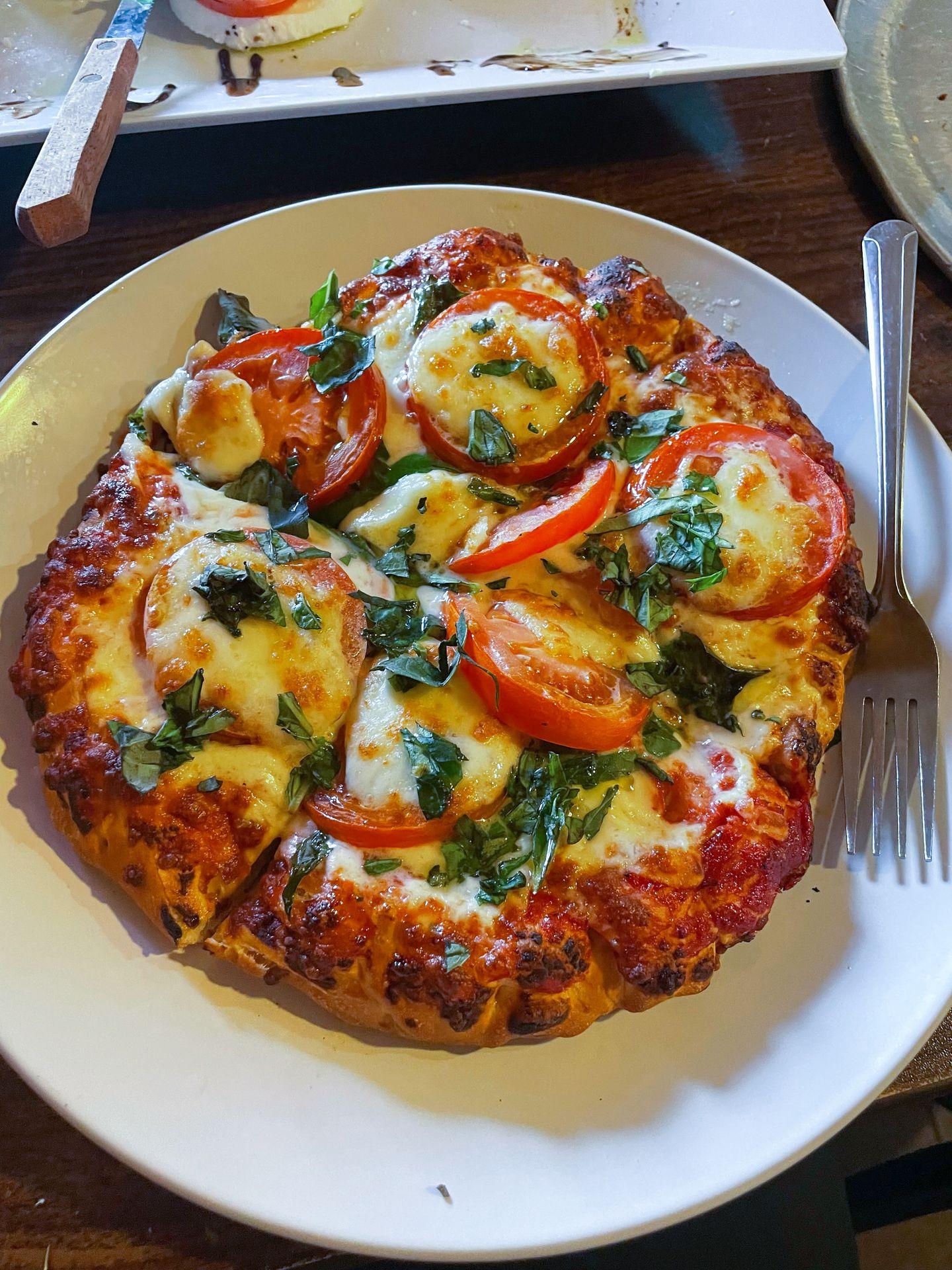 A small pizza topped with cheese, tomatoes and basil.