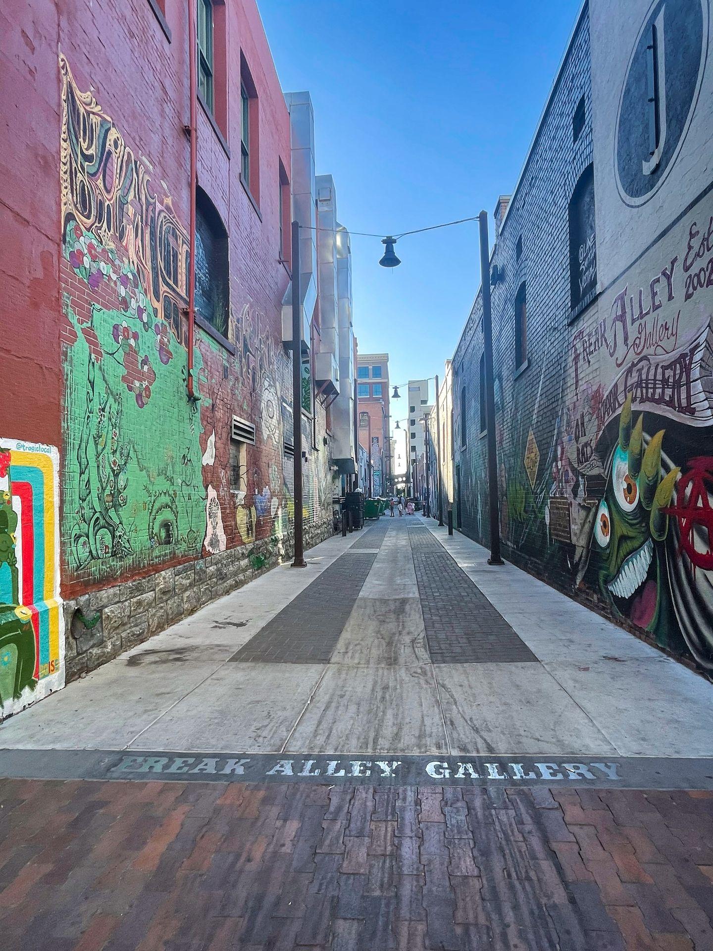 Looking down the Freak Alley gallery with paintings on both sides.