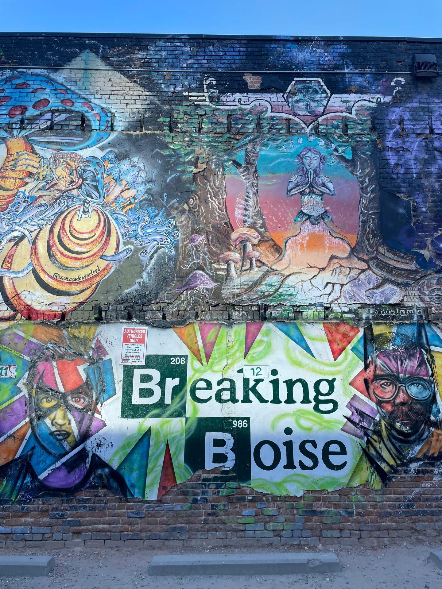 A wall covered in murals, including a piece of art that reads "Breaking Boise" and resembles the "Breaking Bad" logo
