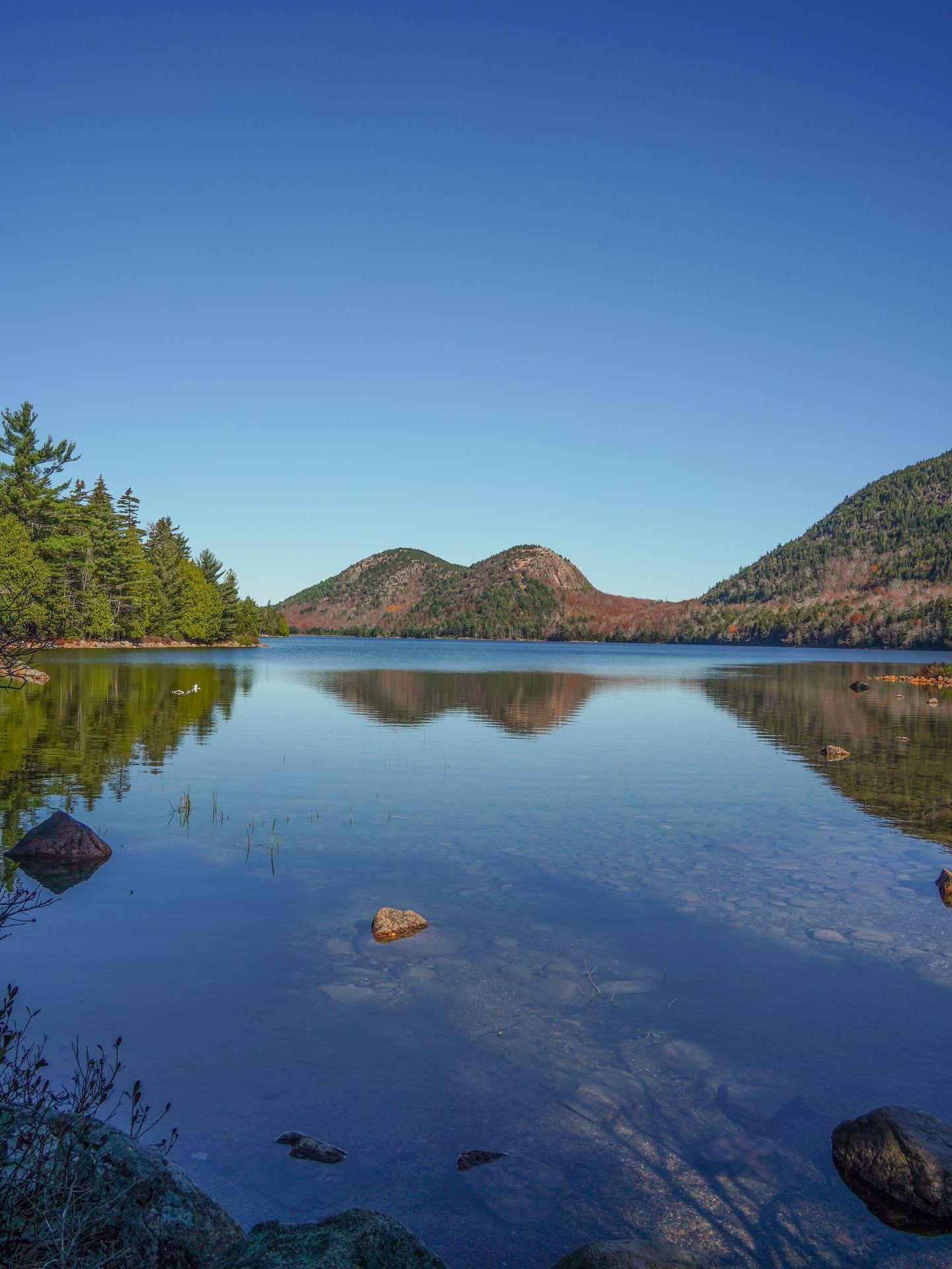 Looking across Jordan Pond at two round mountains reflecting in the water.