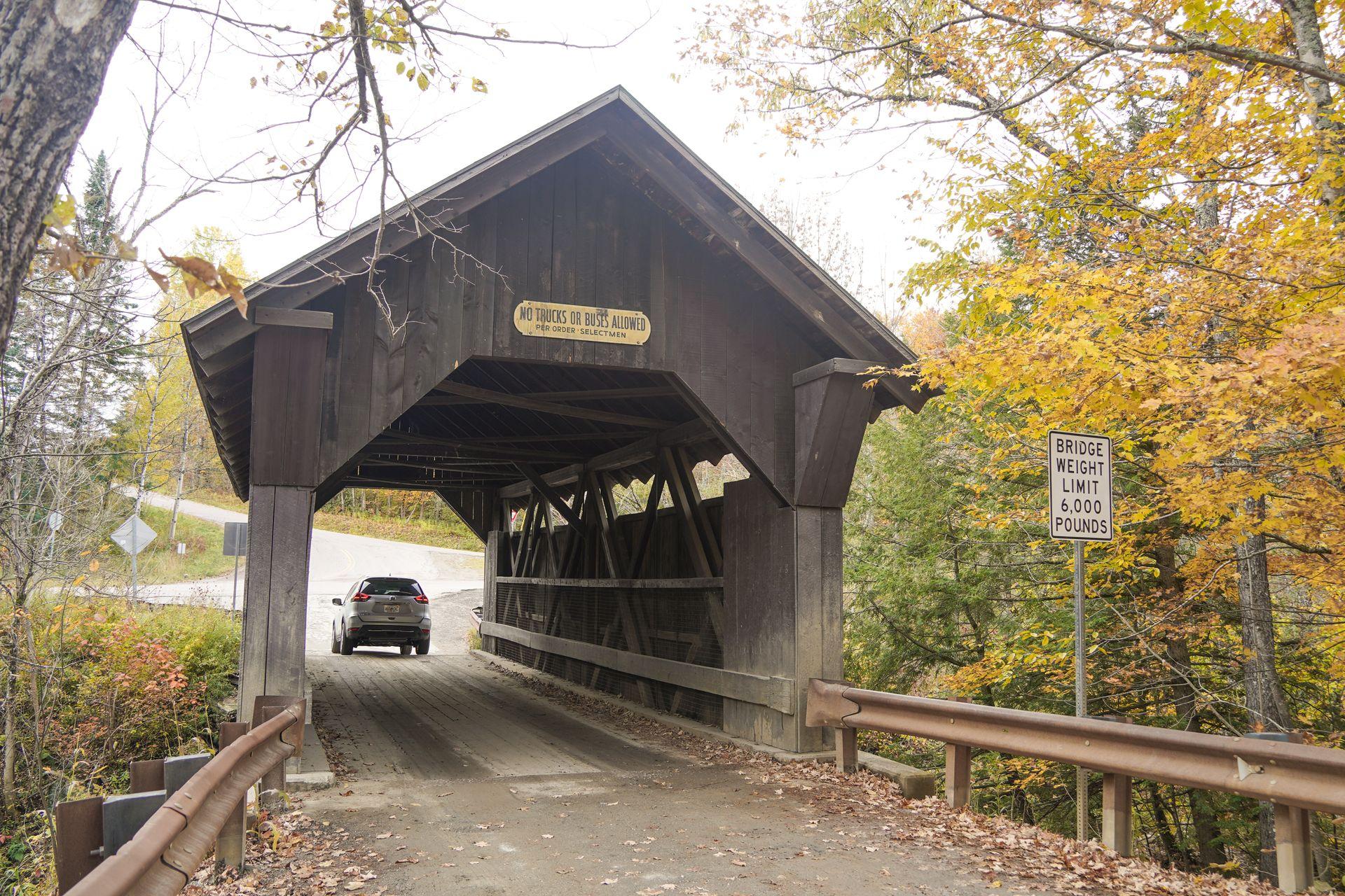 A car driving through a wooden covered bridge in Vermont.