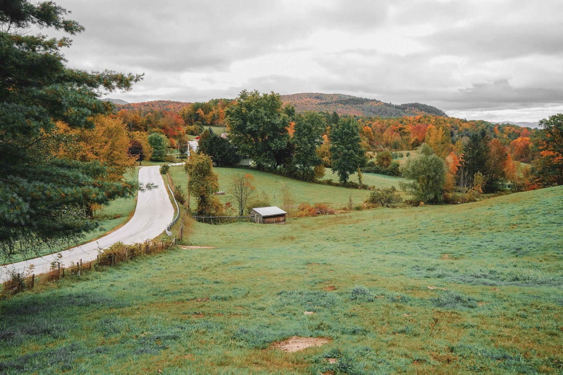 Looking down a hill at Baird Farm with hills covered in fall foliage in the distance.