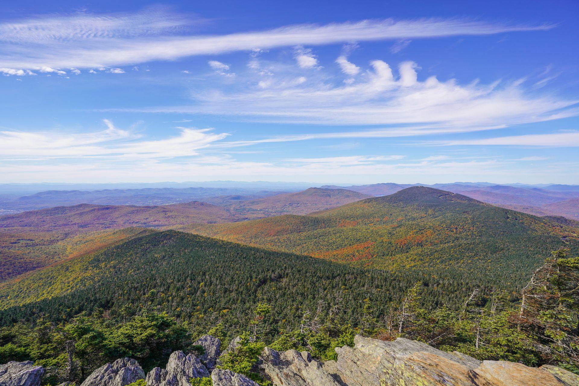 A view of mountains sprinkled with fall foliage seen from the top of Killington Peak in Vermont.