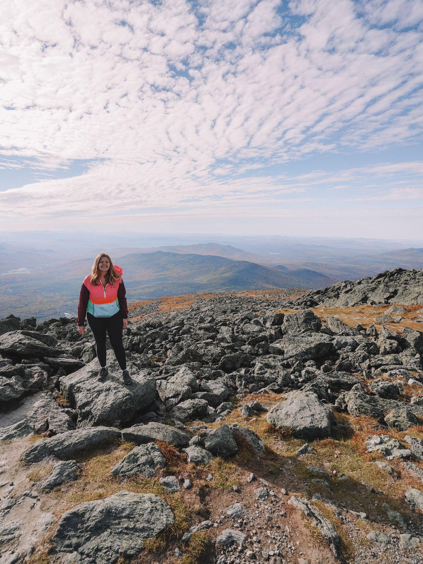 Lydia standing in a rocky area with mountain views in the background.
