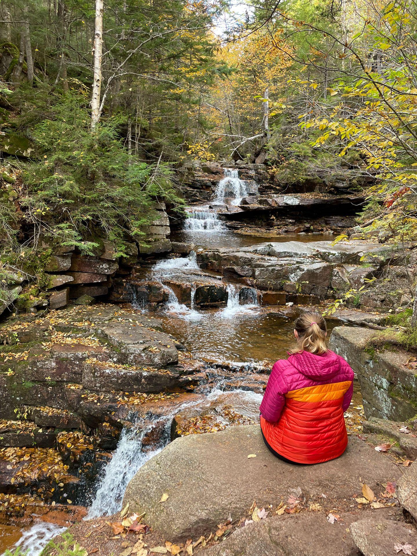 Lydia sitting in front of Bemis Falls along the Bemis Brook Trail