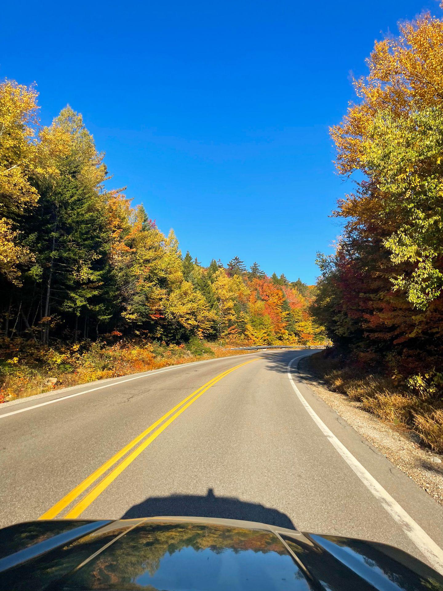 Driving the Kancamagus Highway. The road is surrounded by colorful trees.