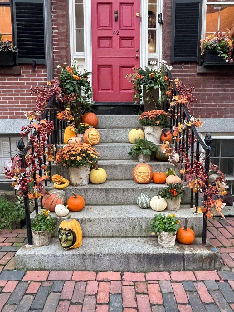 A stoop in the Beacon Hill neighborhood that has several pumpkins and fall decor. Some of the pumpkins have faces carved into them.