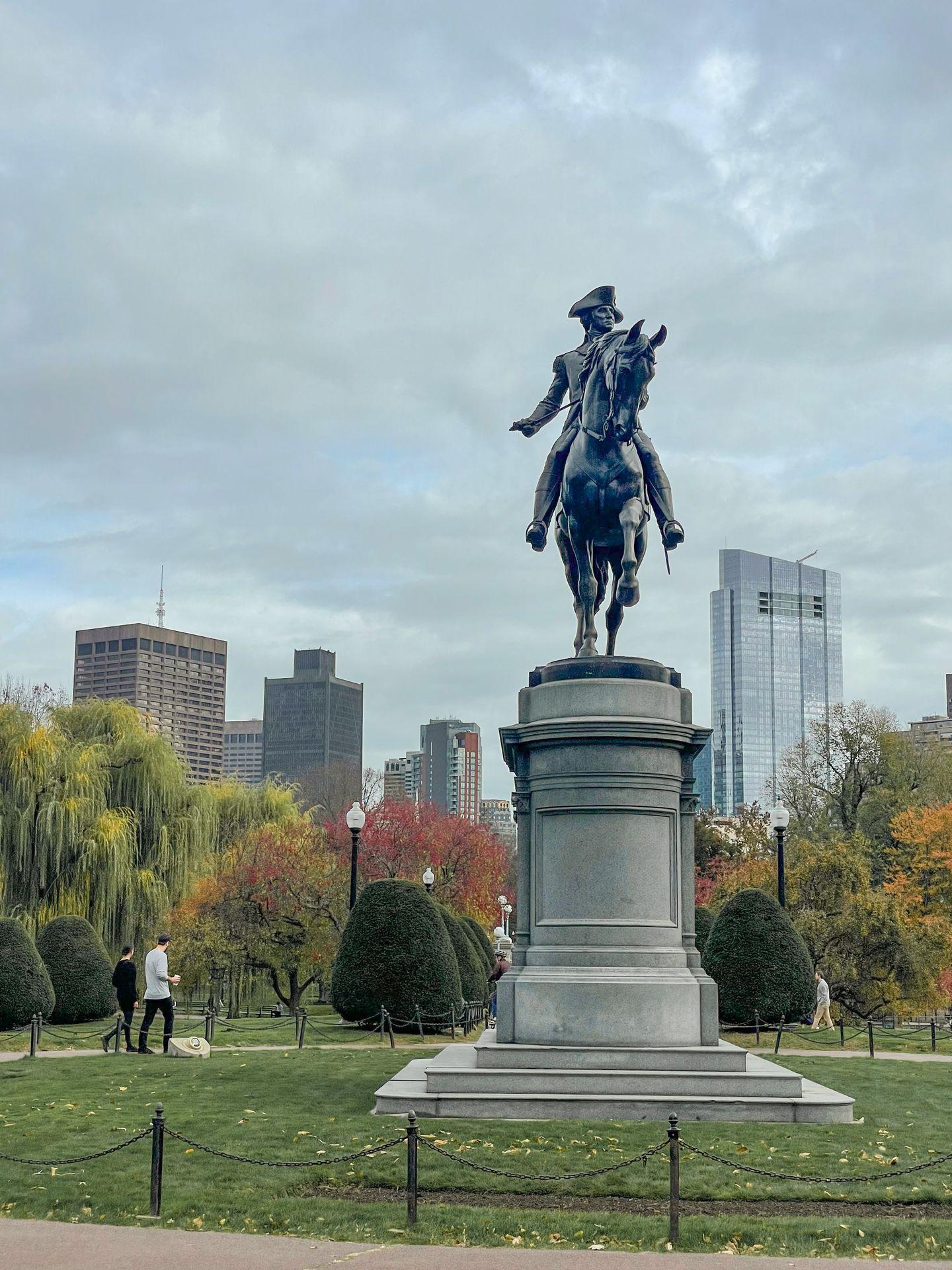 A tall statue with a man on horseback in the Public Garden in Boston.