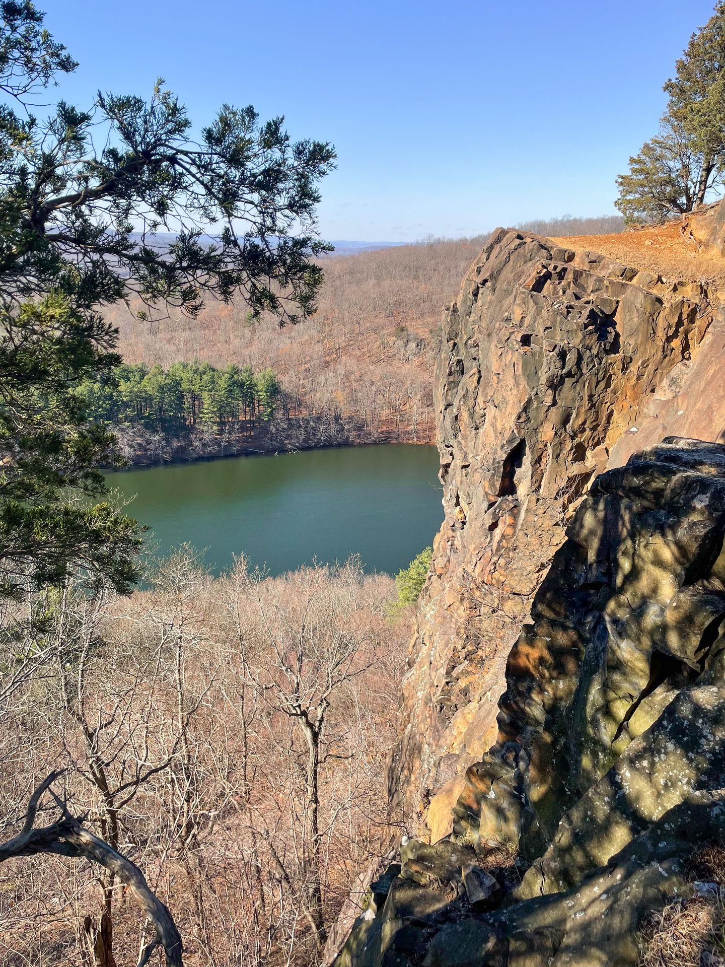 Taken from the top of Chauncey Peak, a rocky cliff stands tall above a lake.