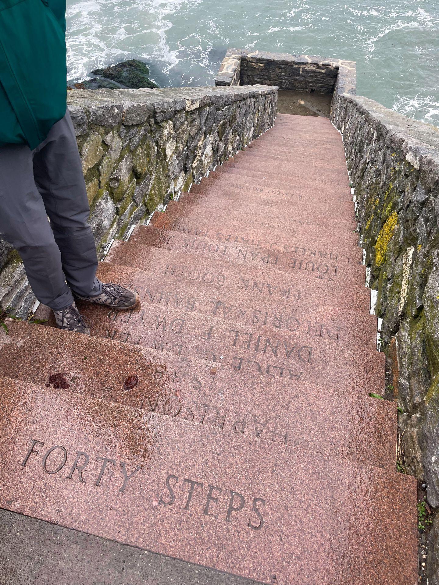 Looking down at reddish steps that leads down closer to the ocean. The top step reads 'Forty Steps'
