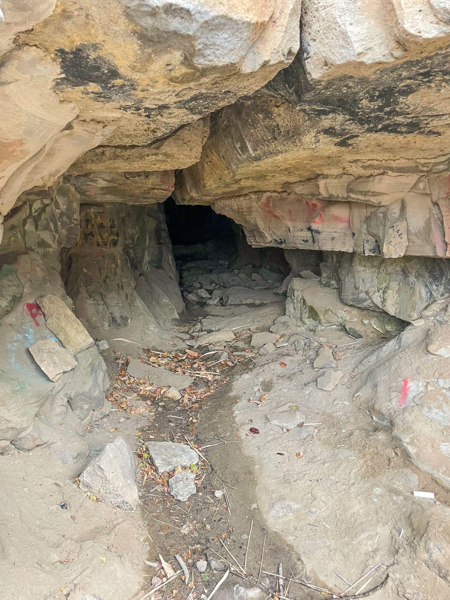 A small cave with a few instances of graffiti on the rocks.