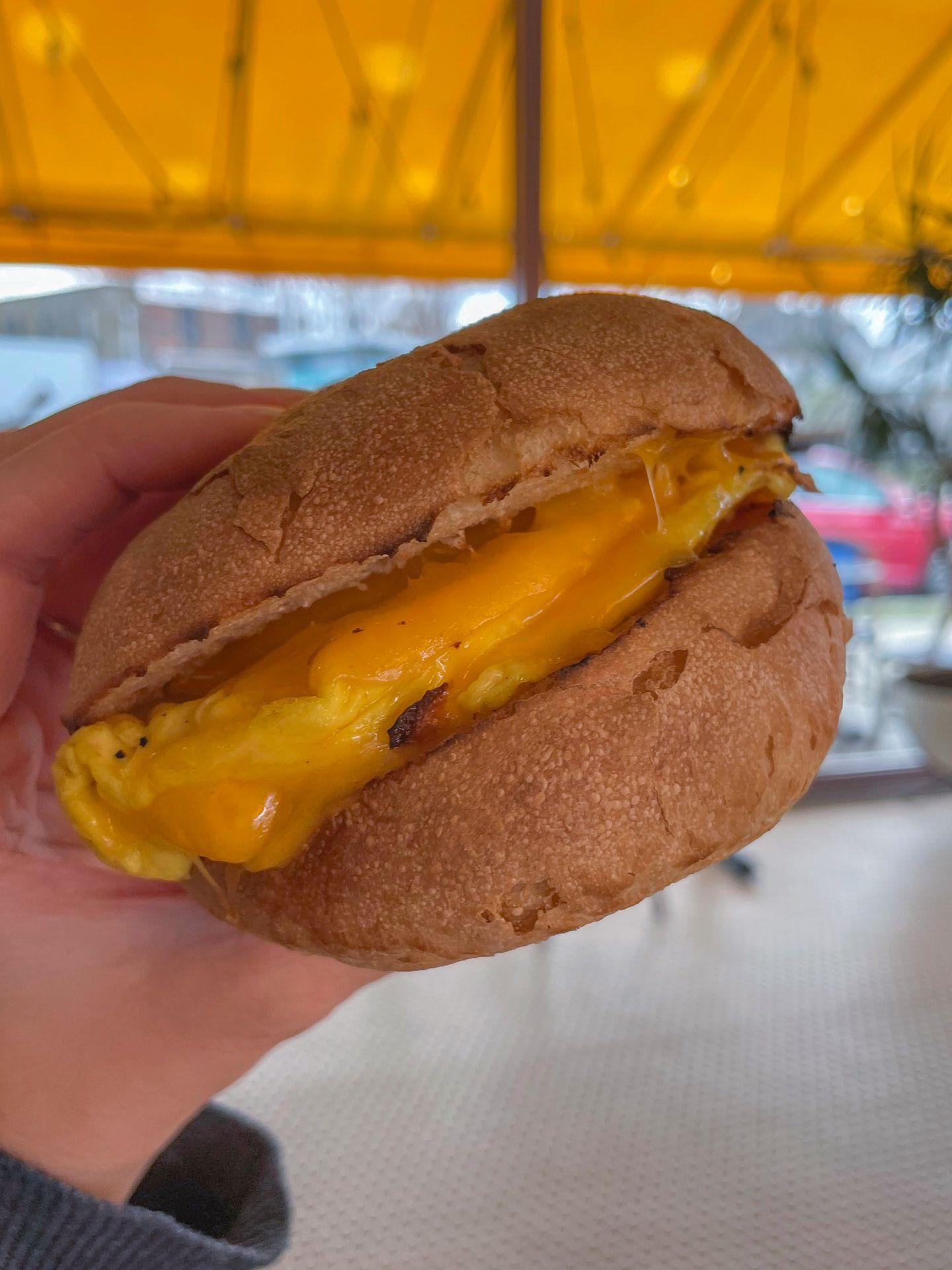 A breakfast sandwich made with a fluffy roll and filled with egg and melted cheese.