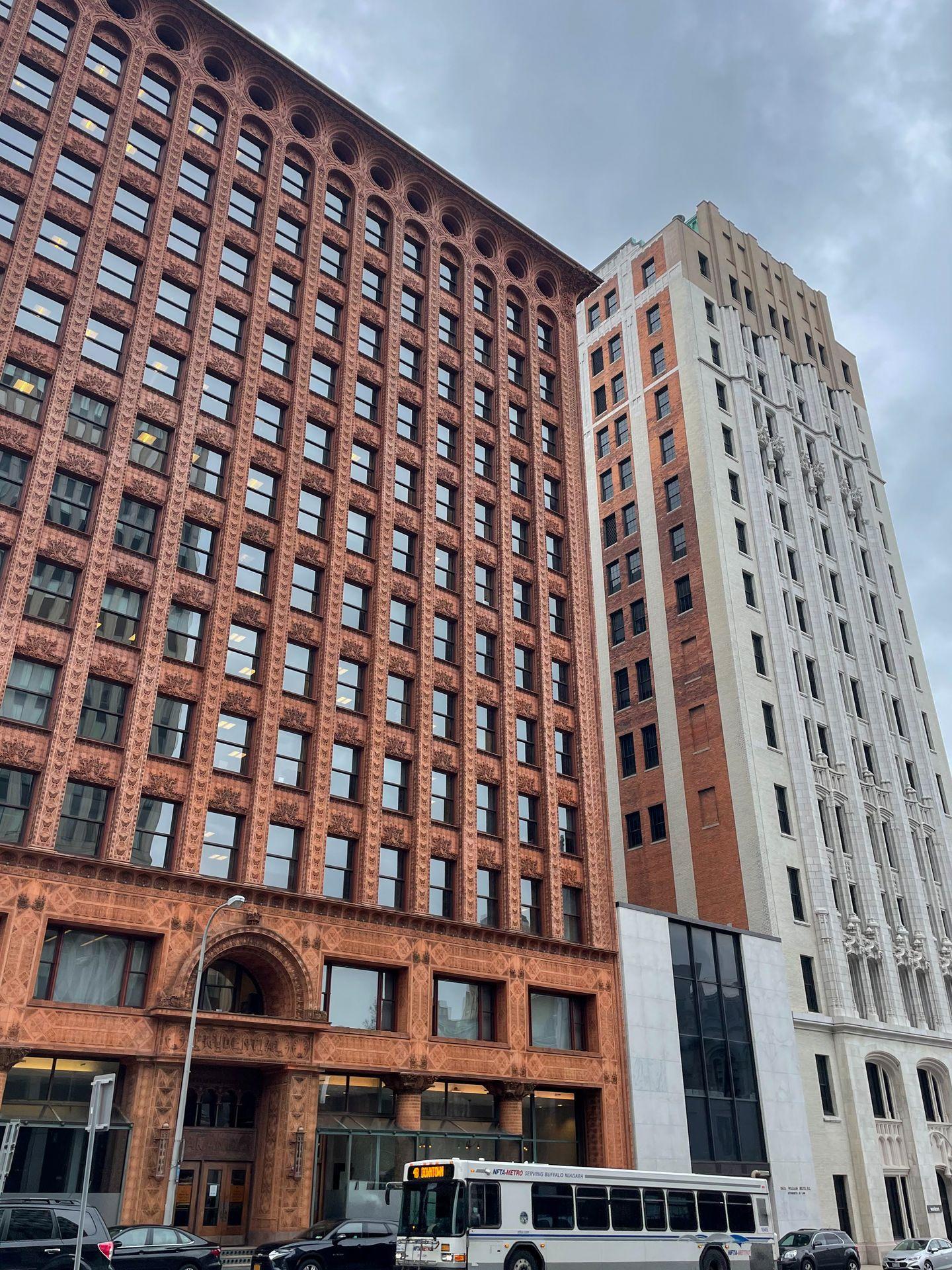 A tall brown buillding next to a white building in downtown Buffalo.