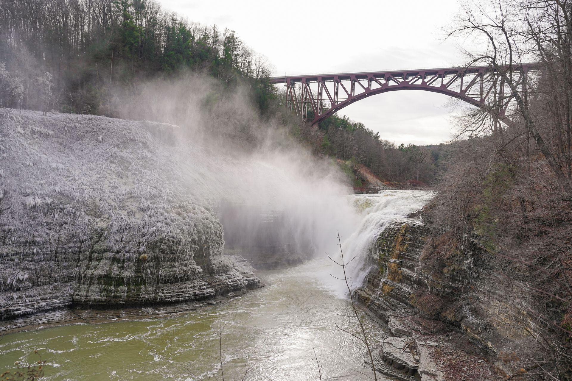 A view of Upper Falls in Letchworth State Park. There is a dusting of snow and ice on the rocks next to the waterfall.