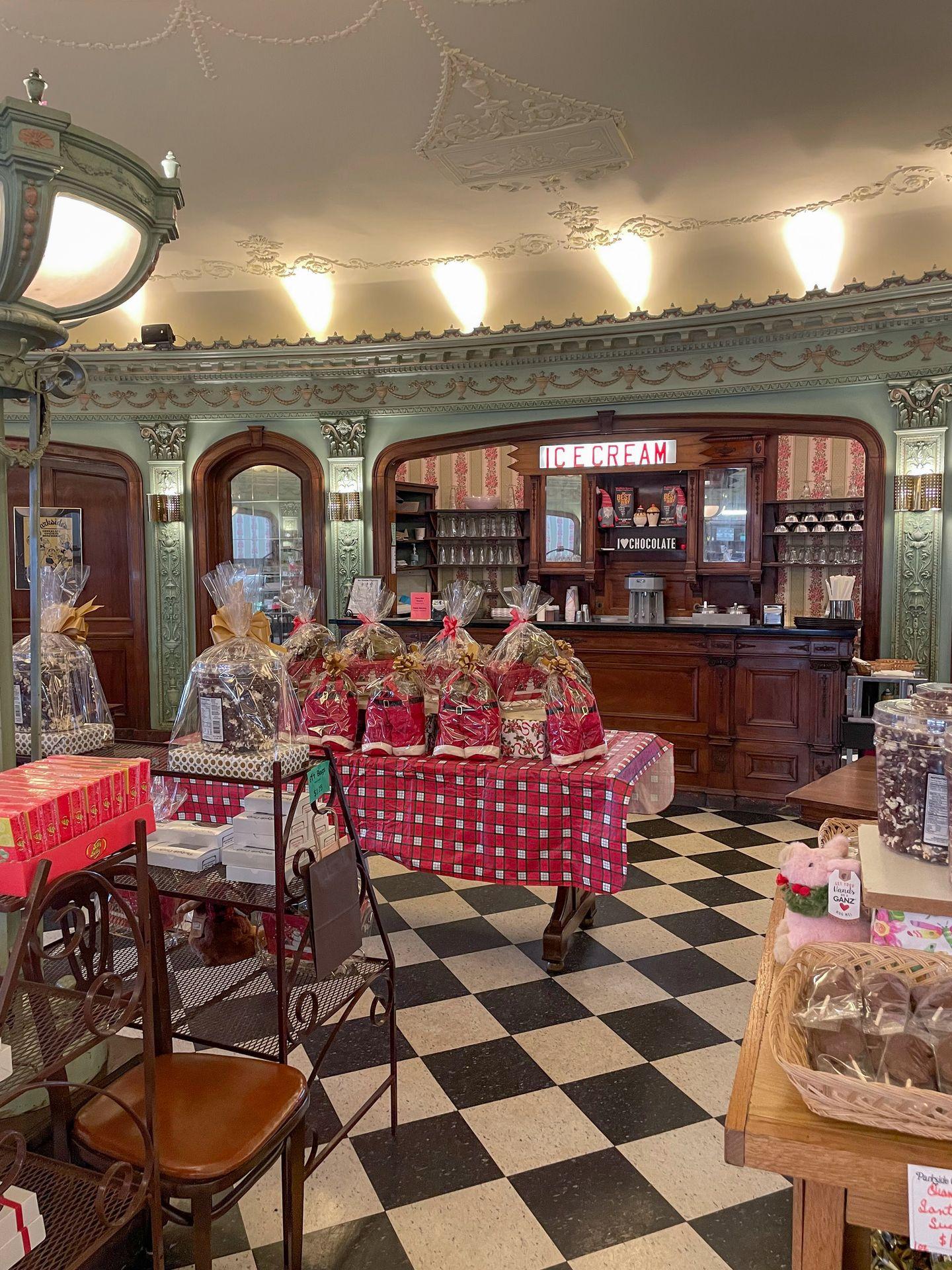 The interior of Parkside Candy, which includes a black and white checker floor, intricate detailing on a green wall and a white ceiling and a wooden built-in cabinet that reads 'ice cream.'