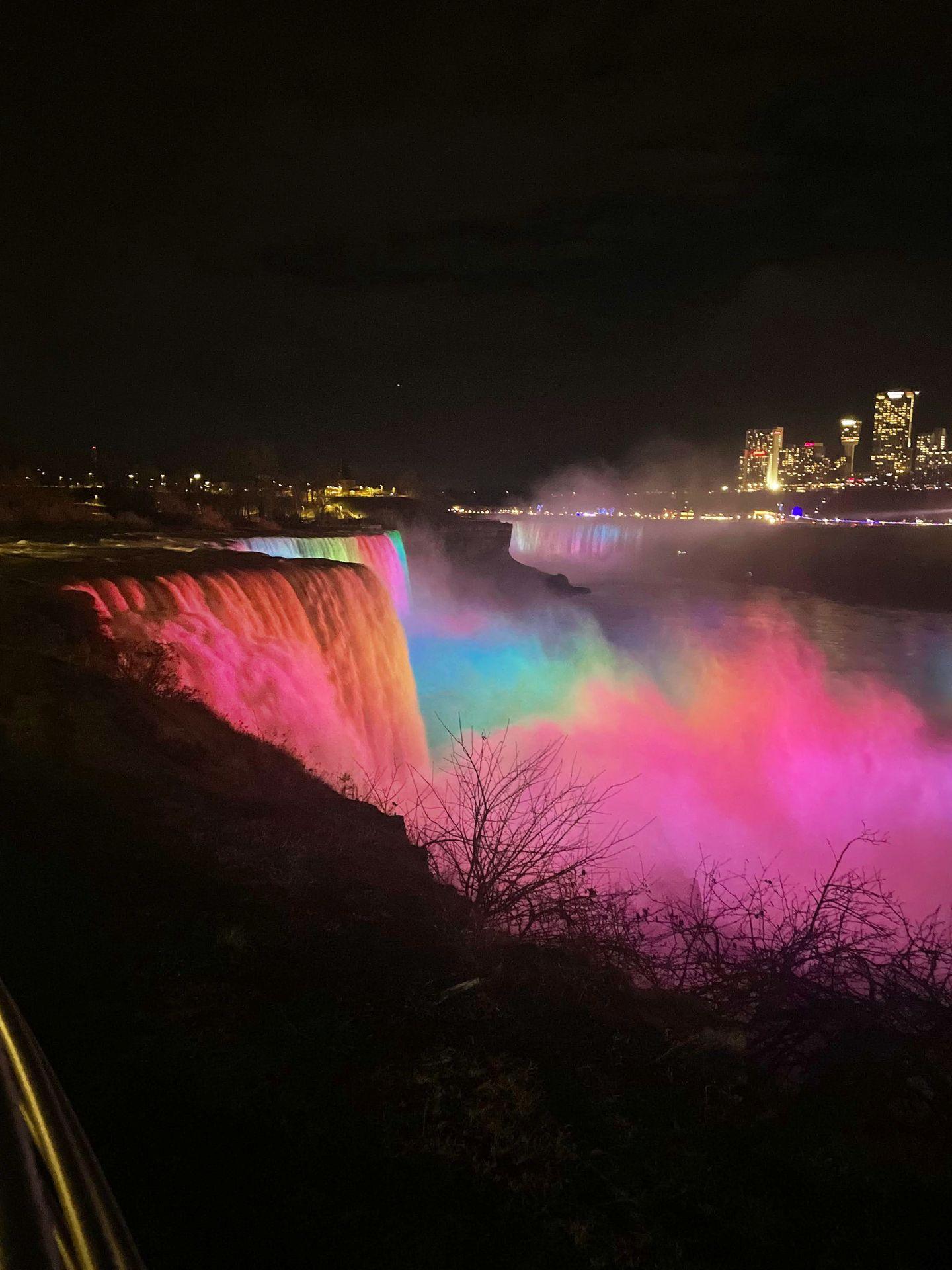American Falls lit up with rainbow lights at night.