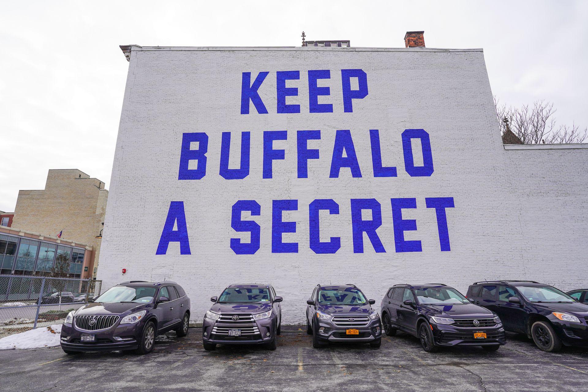 A white wall that reads 'Keep Buffalo a Secret' in large blue letters.