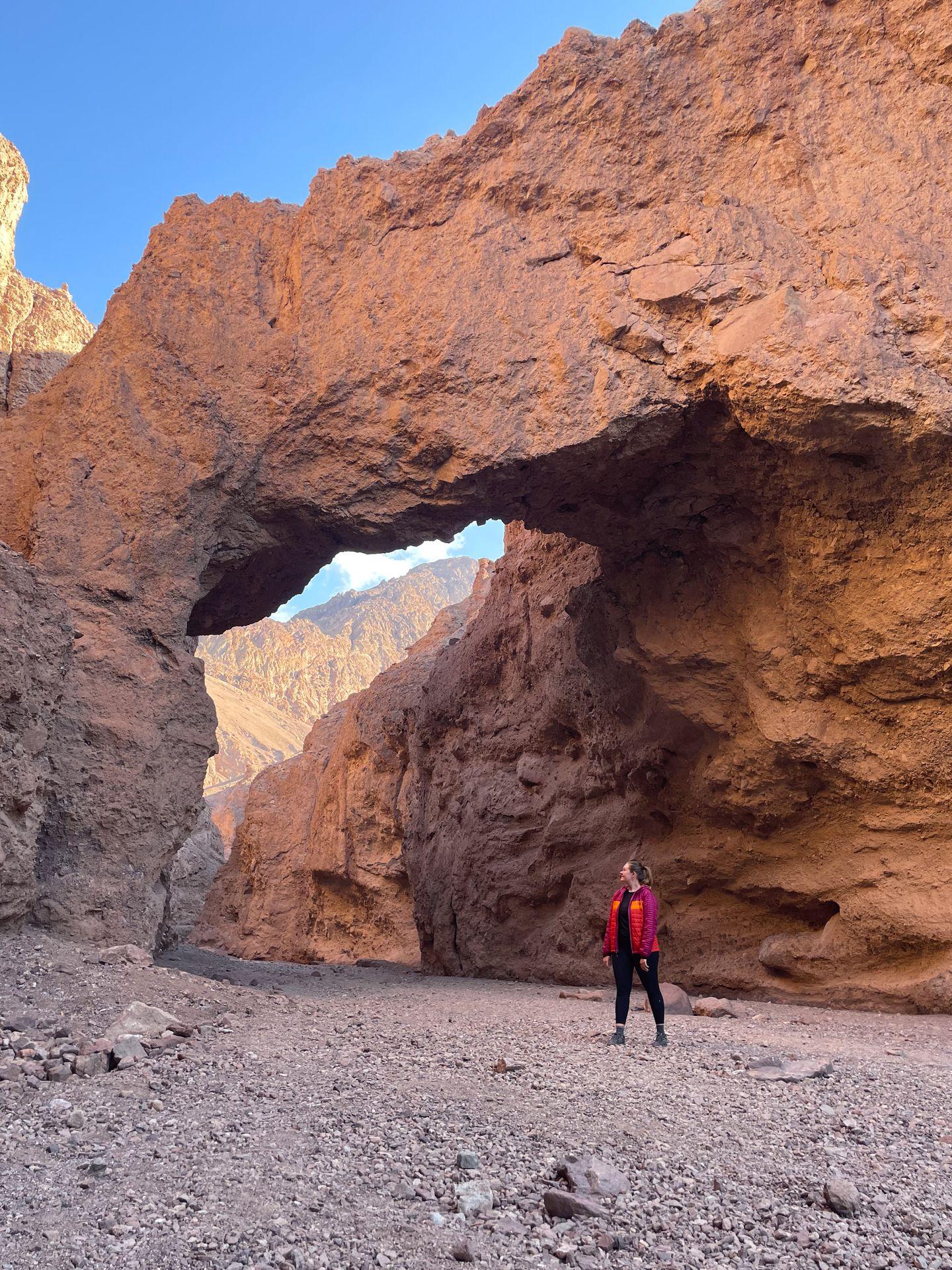 Lydia standing under the natural bridge on the Devil's Bridge Trail in Death Valley.