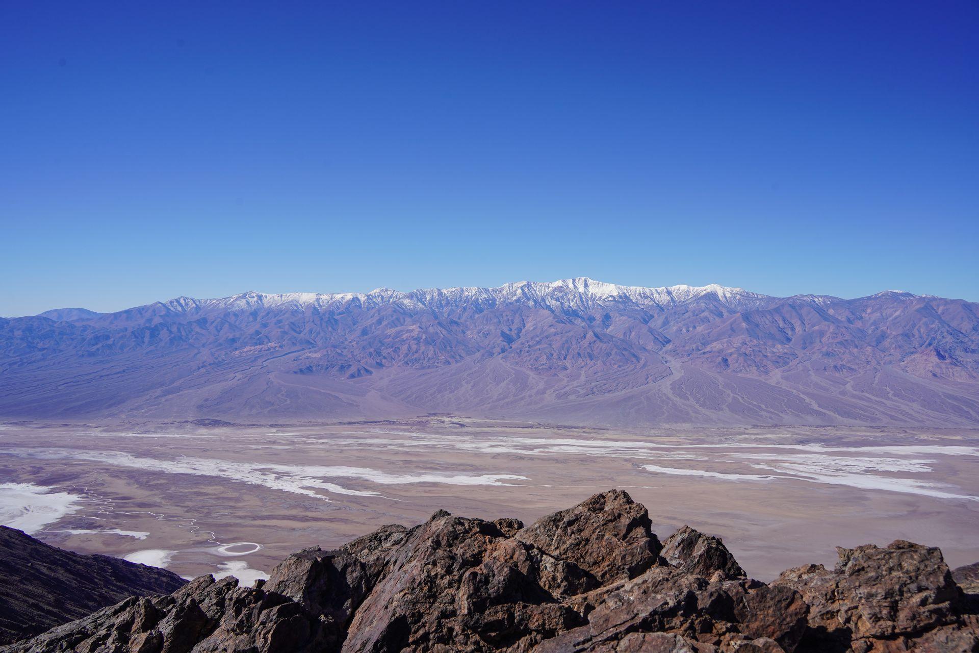 Looking down at an expansive valley full of salt flats from the Dante's View overlook. You can see mountains in the distance from the other side of the valley.