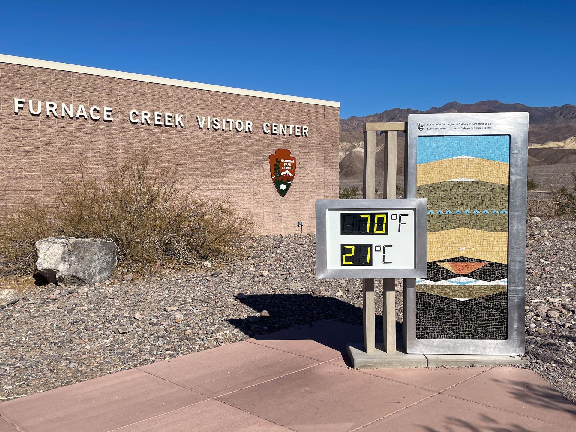 A temperature reading of 70 degrees fahrenheit and 21 degrees celcius outside of the Furnace Creek Visitor Center