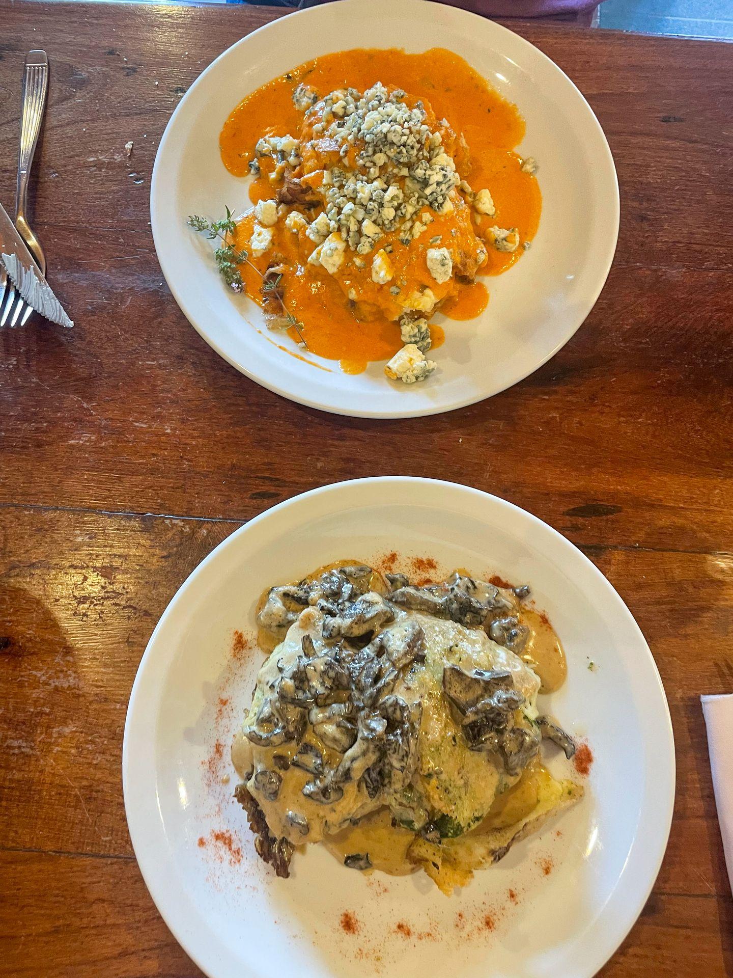Two plates of ravioli. One is topped with mushrooms and the other is topped with an orange sauce and bleu cheese crumbles.
