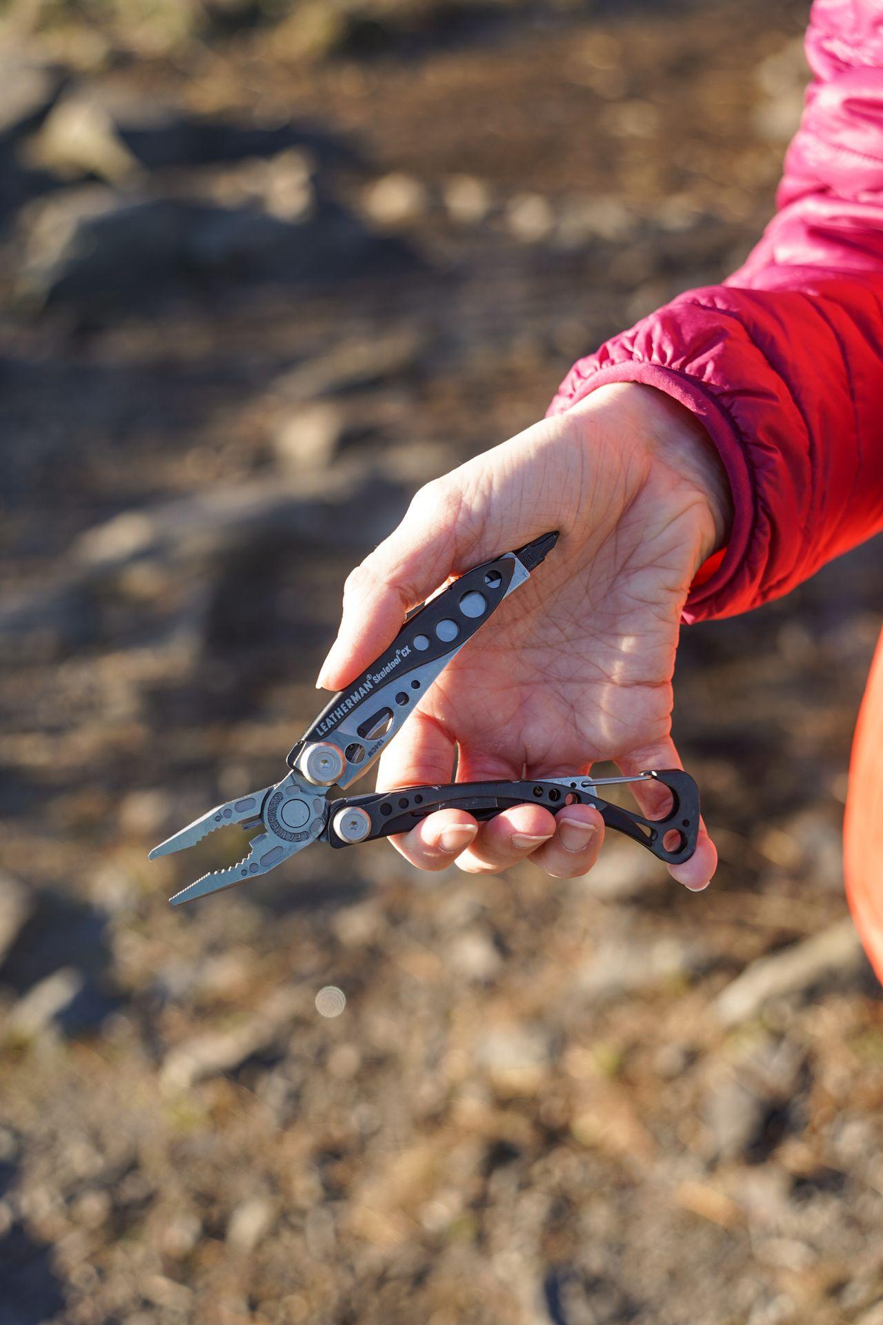 Holding the Leatherman Skeletool, a multi-tool that is black and silver.