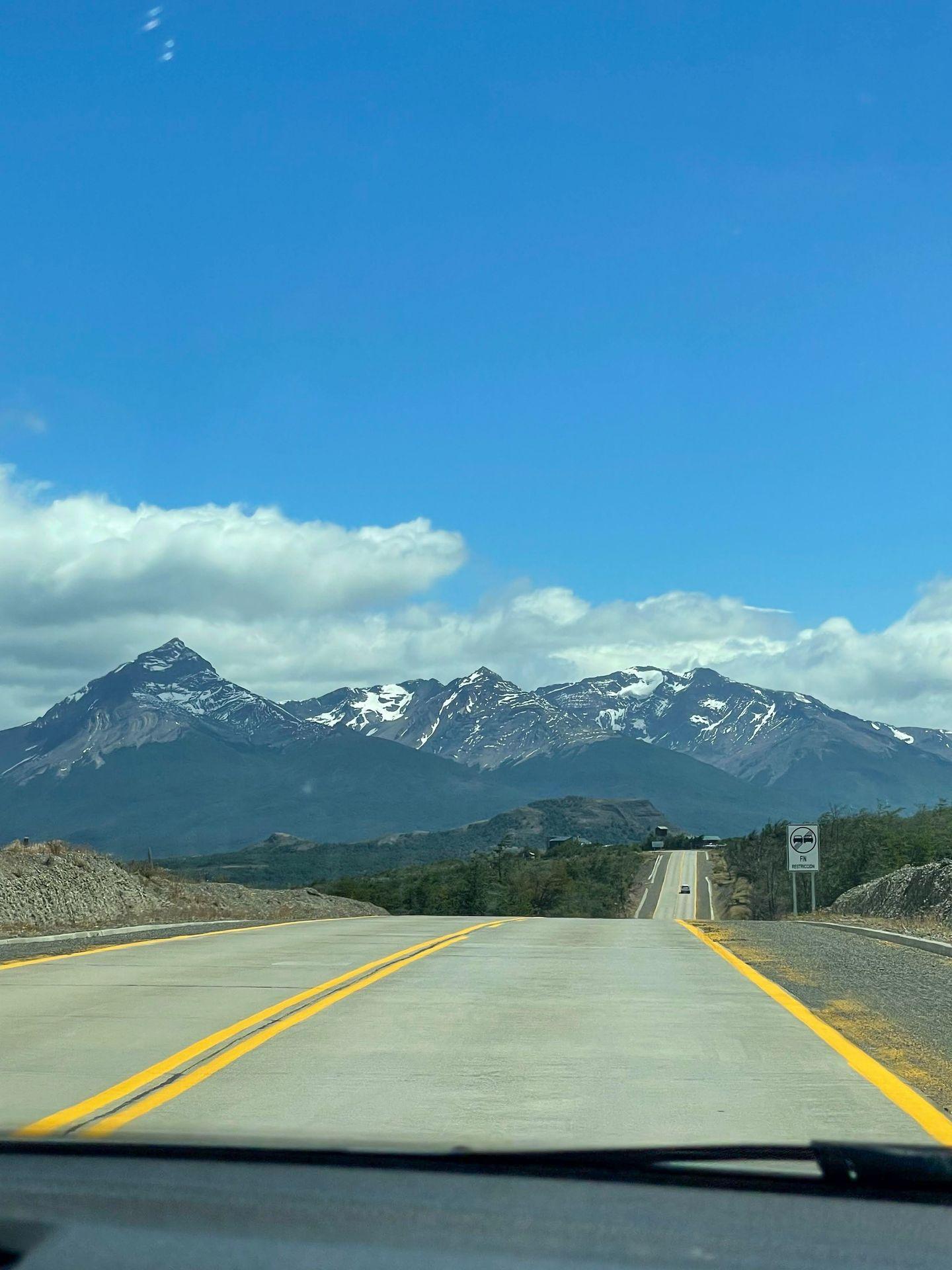 A road in Patagonia that is leading to tall mountains in the distance.
