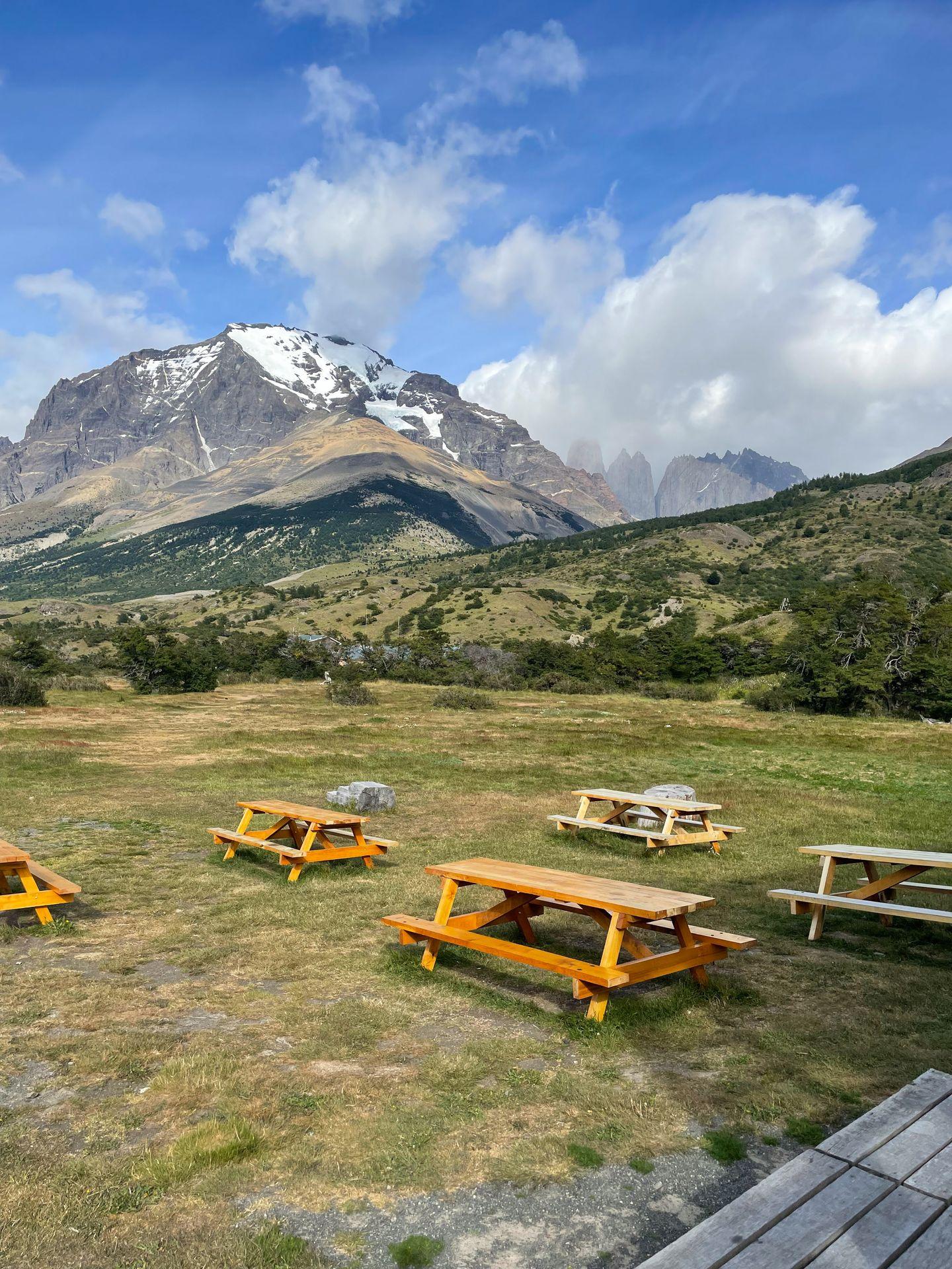 A few picnic tables in a valley with a mountain in the distance.