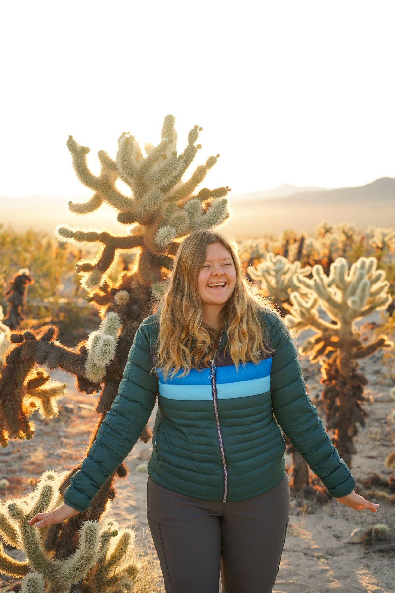 Lydia standing in front of glowing cacti at Cholla Cactus Garden during sunrise.