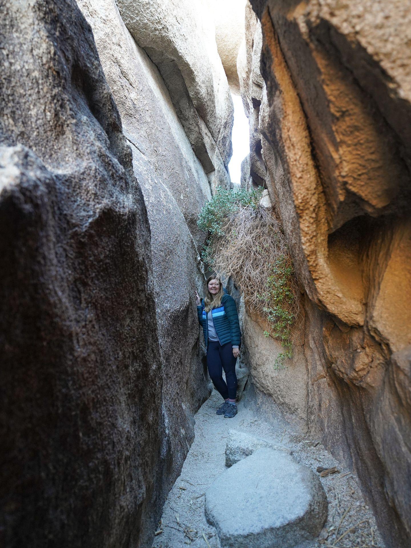 Lydia standing inside of a narrow slot canyon and leaning against one side.