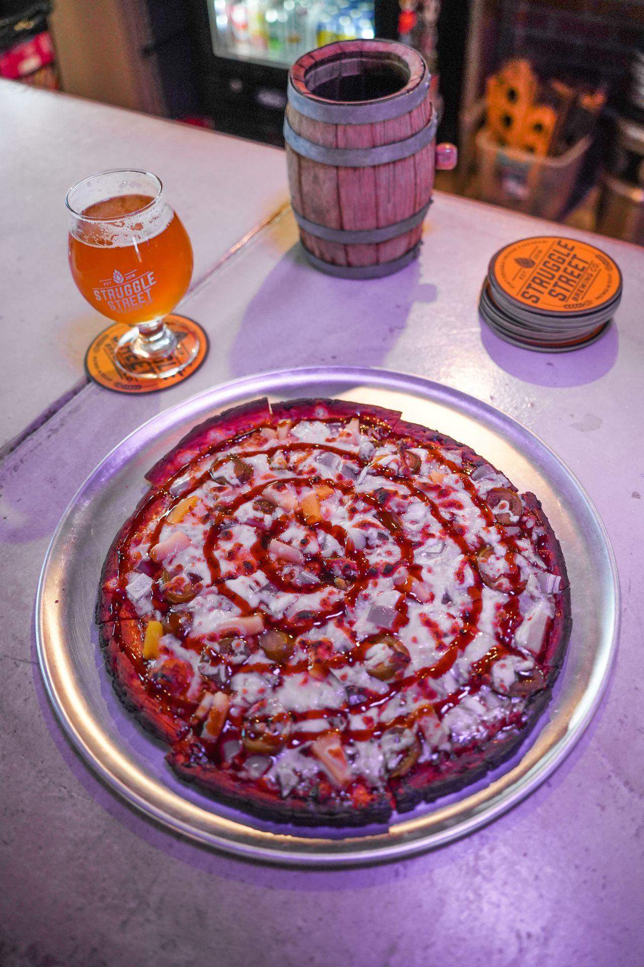 A pizza topped with red hot sauce spiraling around the pizza.
