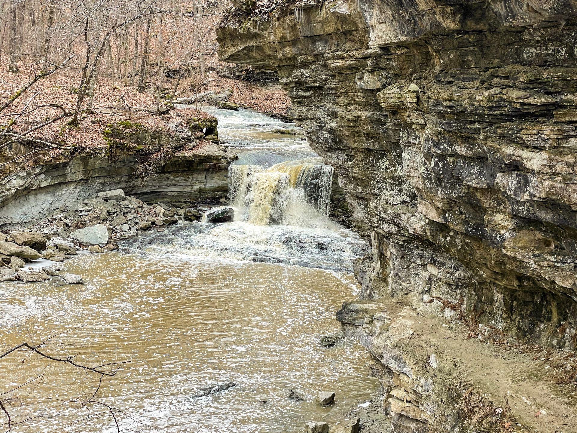 A waterfall next to a rock overhang in McCormick Creek State Park.