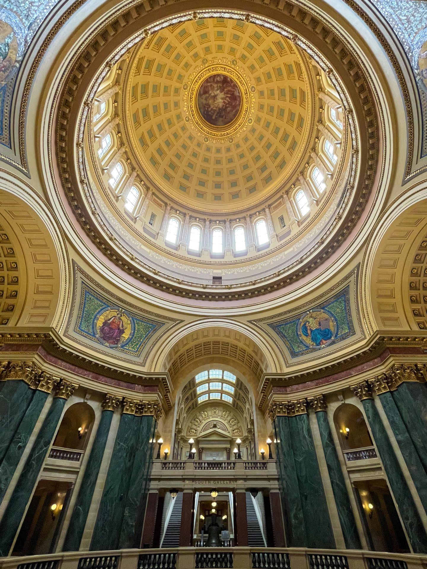 The interior of the dome of the Wisconsin state Capitol building. The interior is ornately decorated in gold and green.
