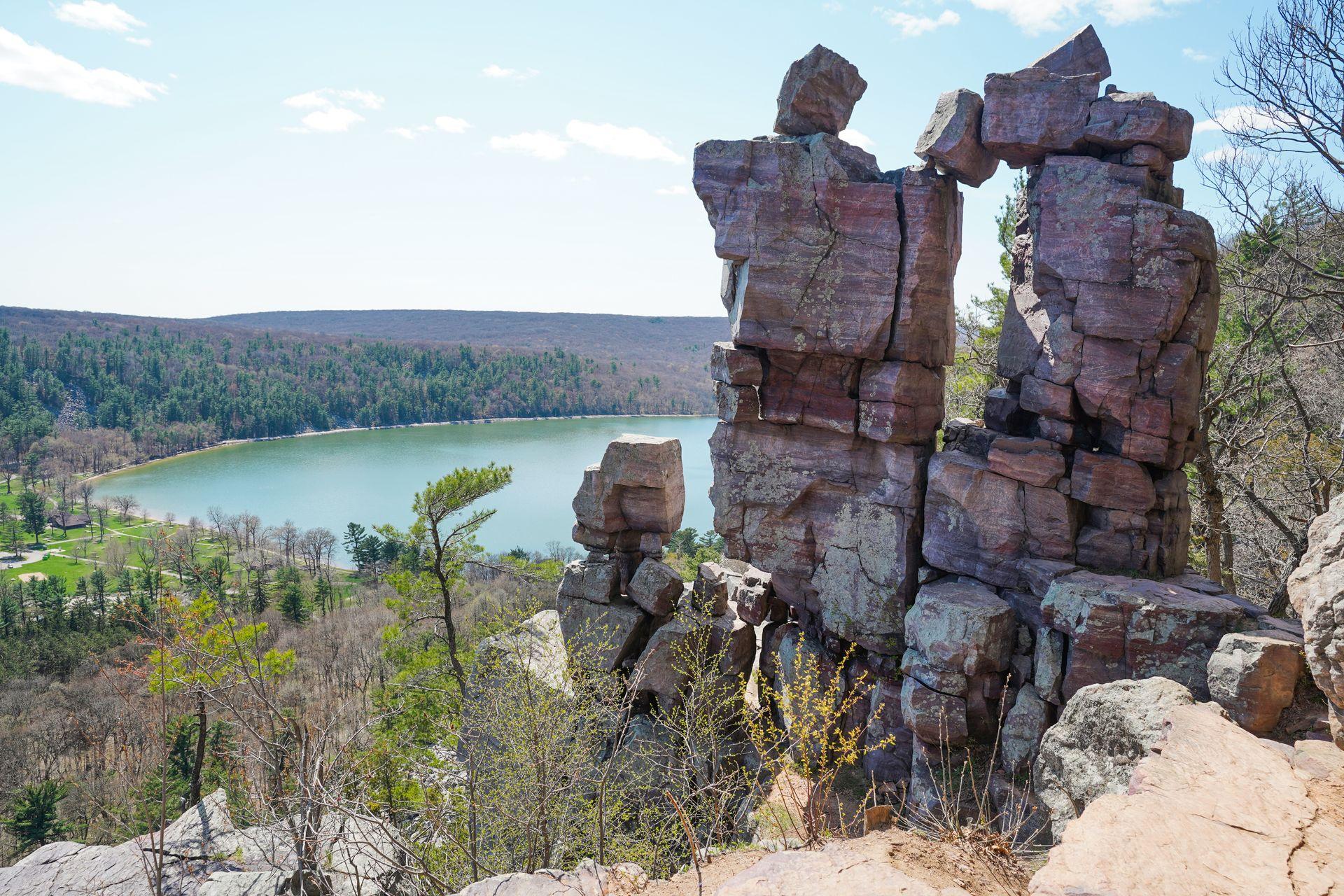 A rock formation that looks as if several rocks have been stacked up to create a doorway. There is a lake in the background.