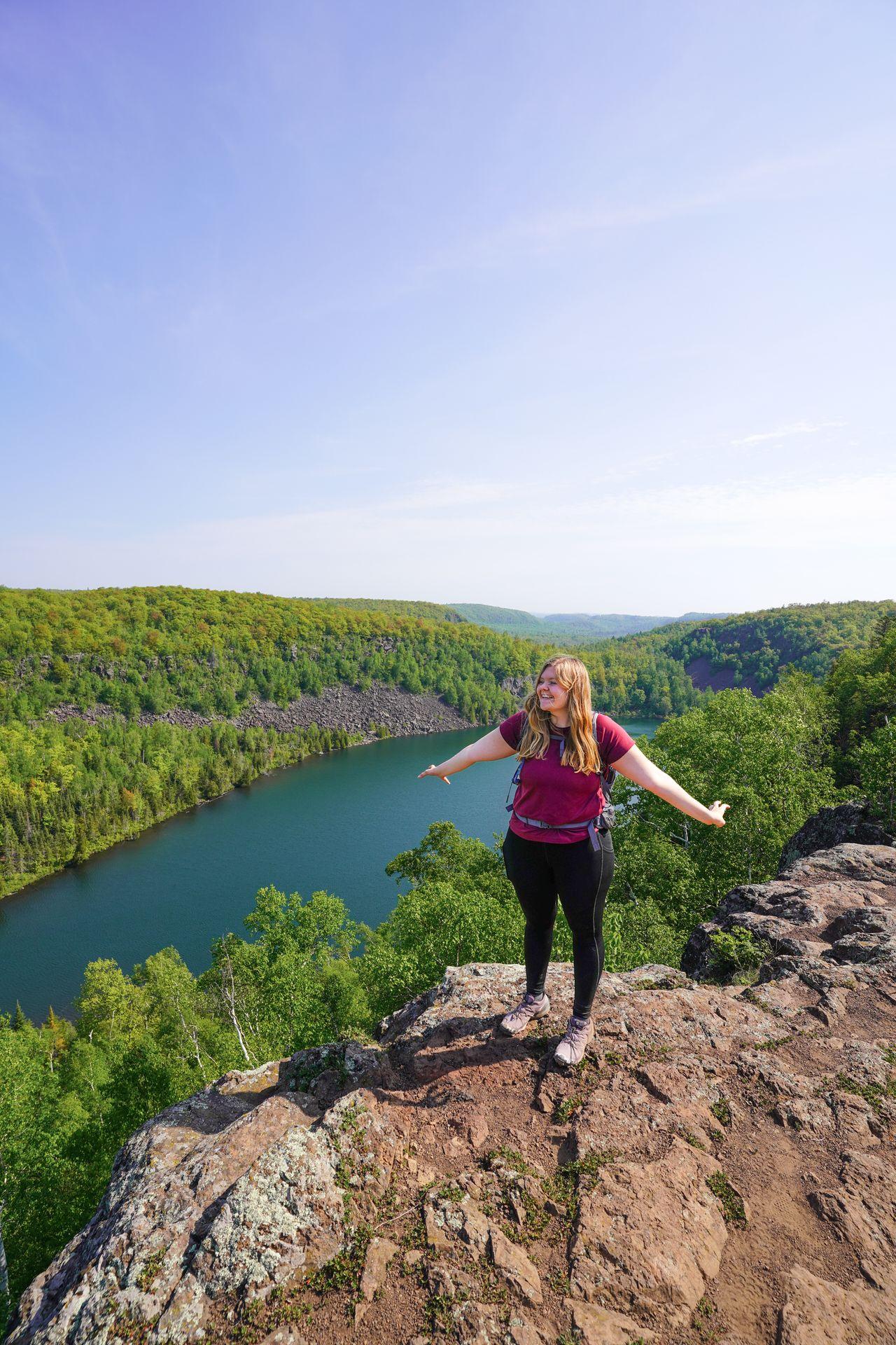 Lydia standing on a cliff with a lake beneath her on the Bean and Bear Lake Trail.