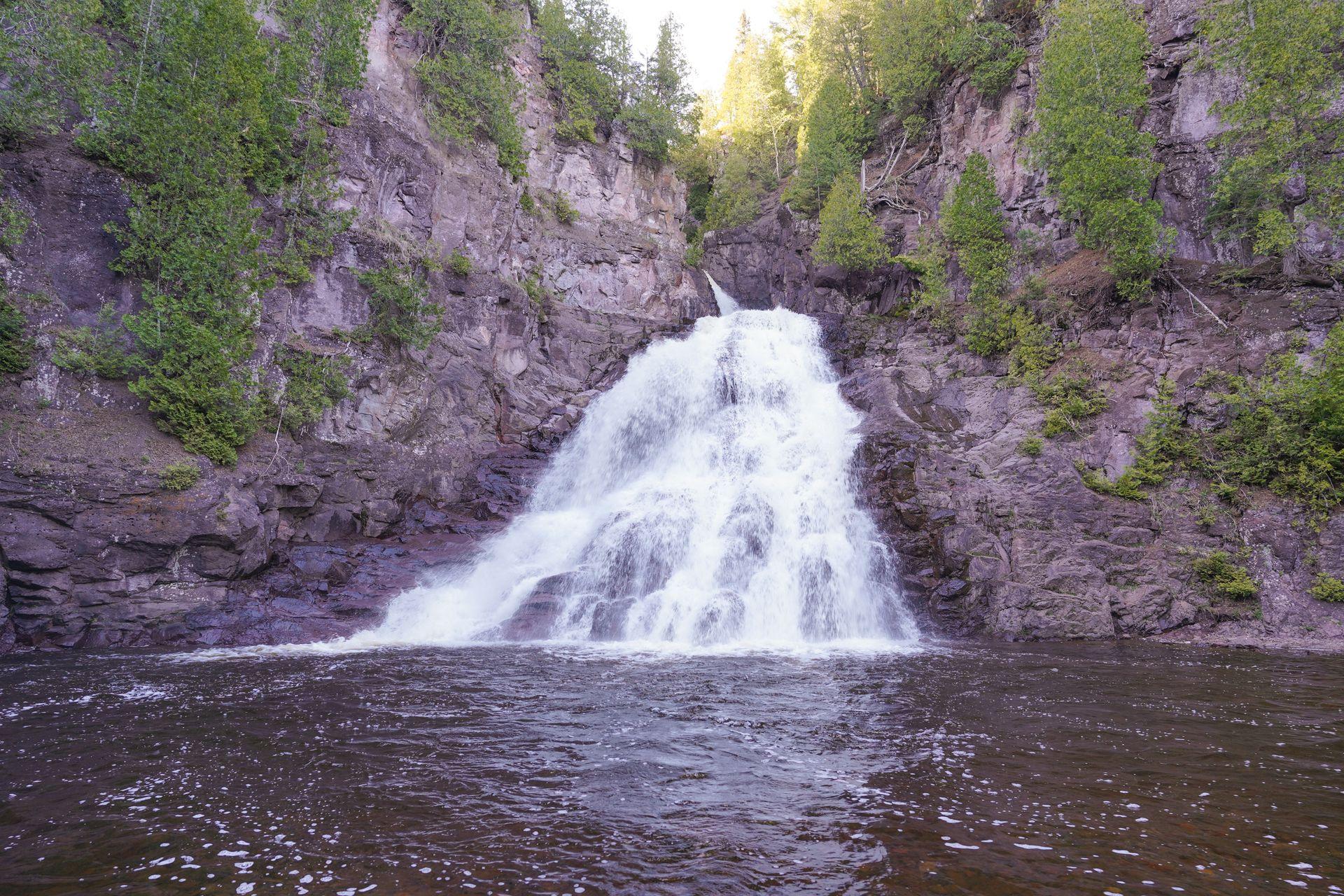 A waterfall cascading down a reddish cliff along the Minnesota North Shore.