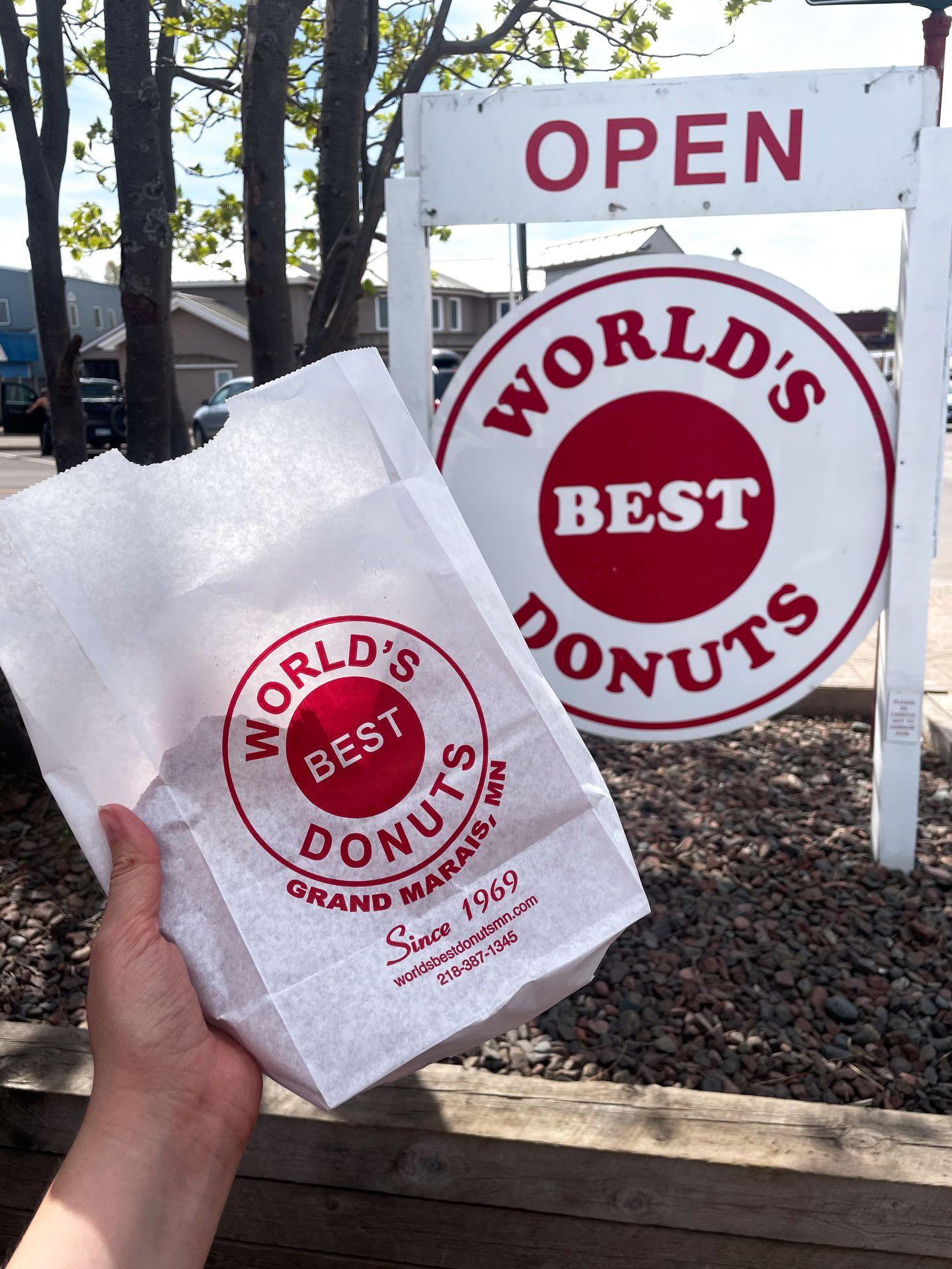 Holding up a bag of donuts in front of World's Best Donuts in Grand Marias, MN.