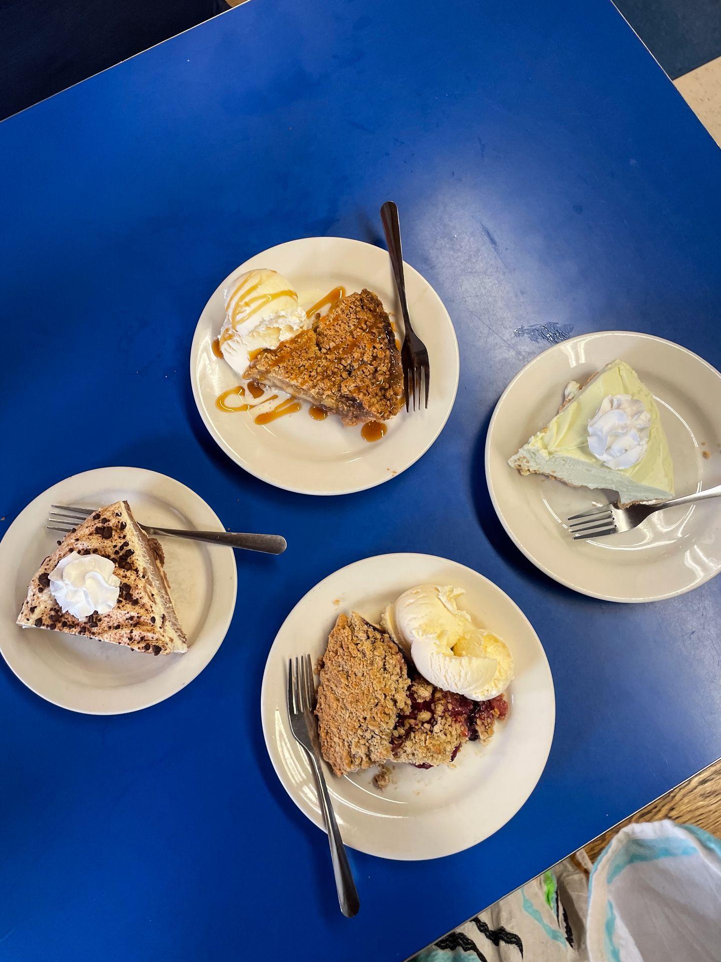 Four slices of pie from Betty's Pies. There are 2 fruit pies, a key lime pie and a chocolate pie. Two are served with ice cream
