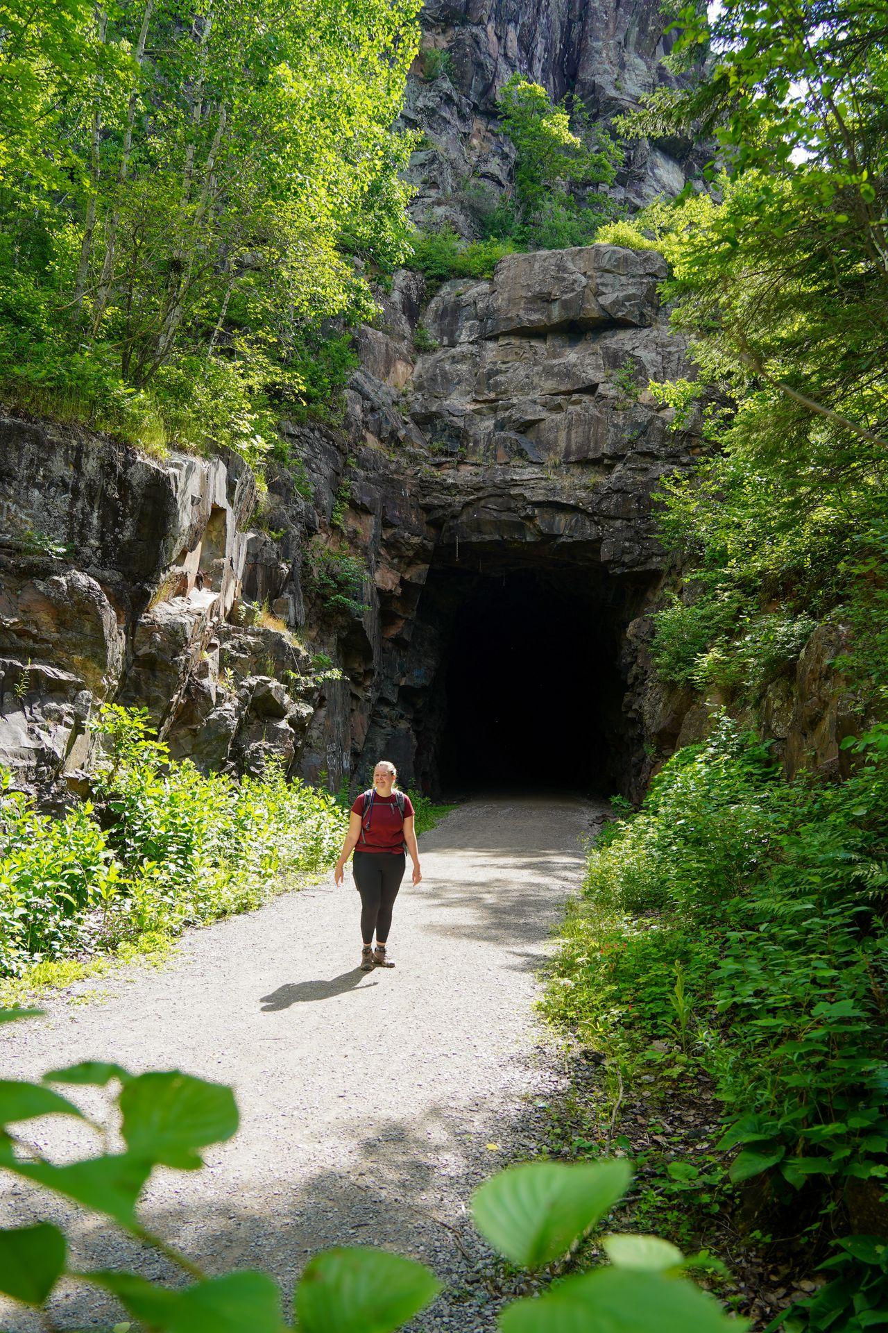 Lydia standing in front of the tall and square Railroad tunnel on the Ely's Peak trail.