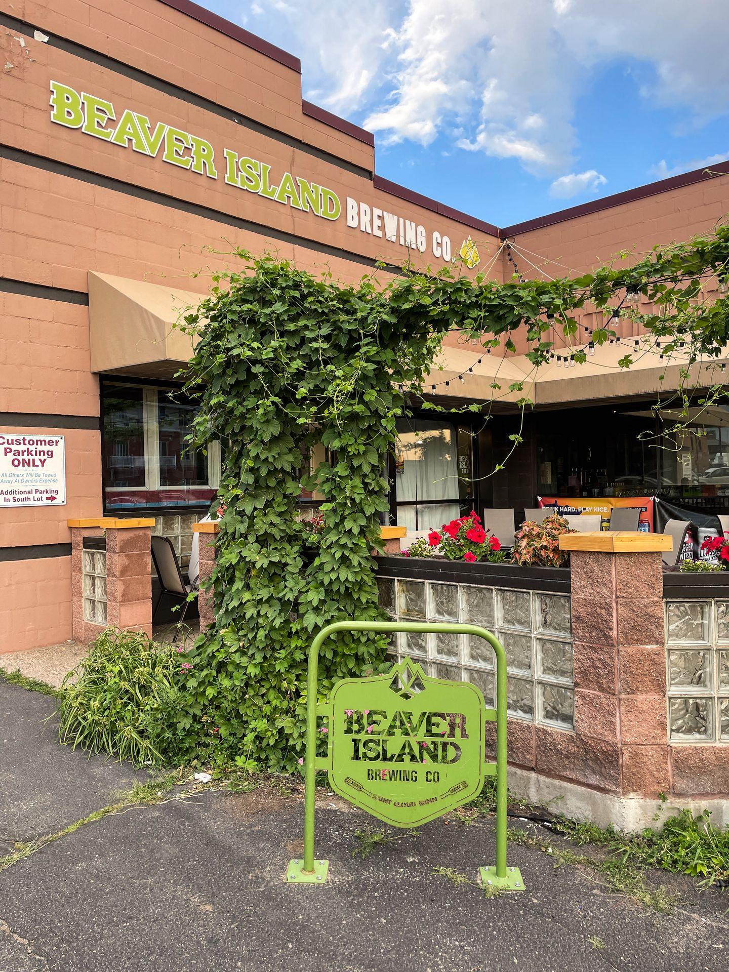 The exterior of Beaver Island Brewing, a building with a green gate and a sign