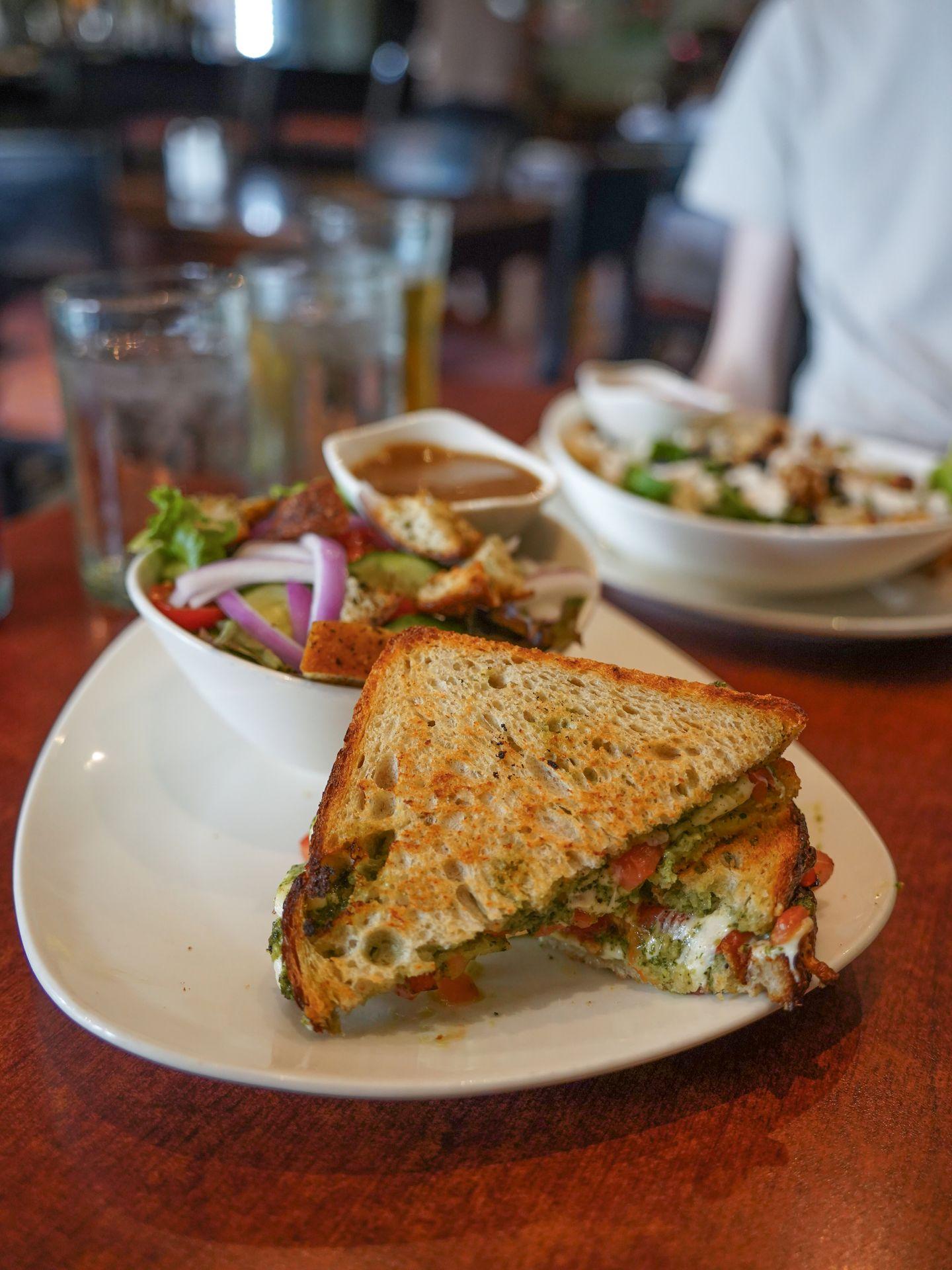 A pesto panini and a salad on a plate at Jules Bistro