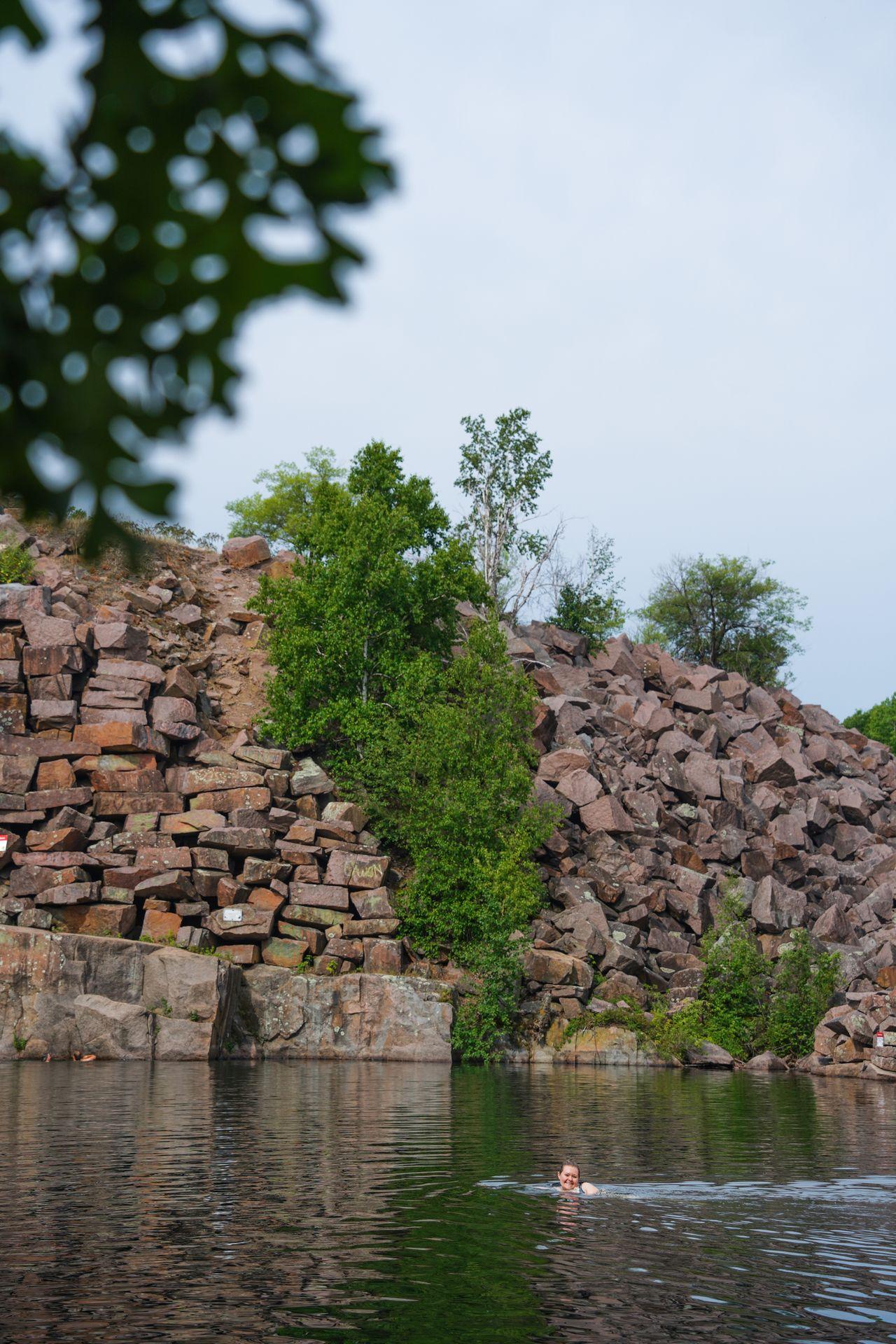 A large piles of quarry rocks next to a pool of water.