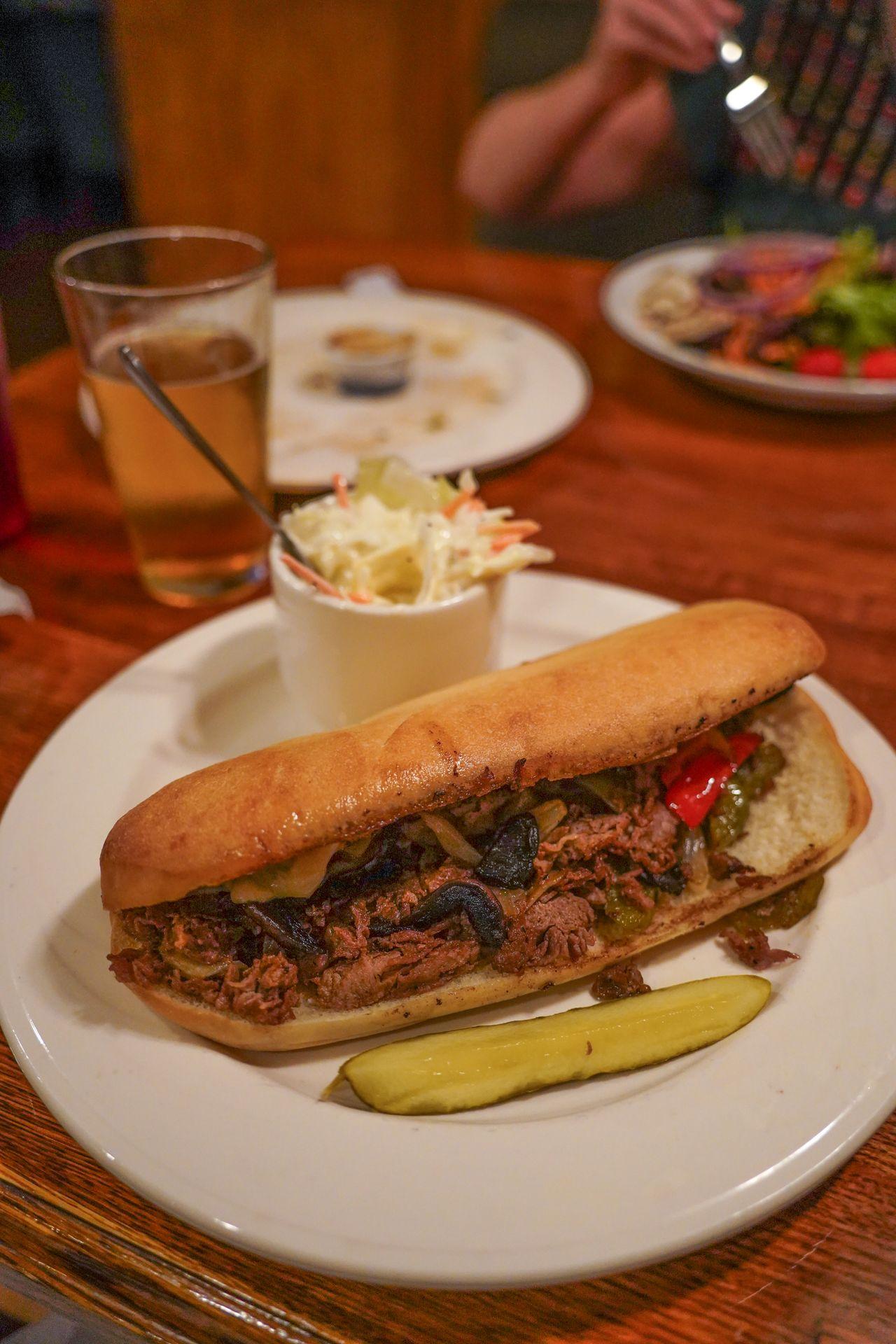 A philly cheesesteak with a pickle next to it from P J Harrigan's.