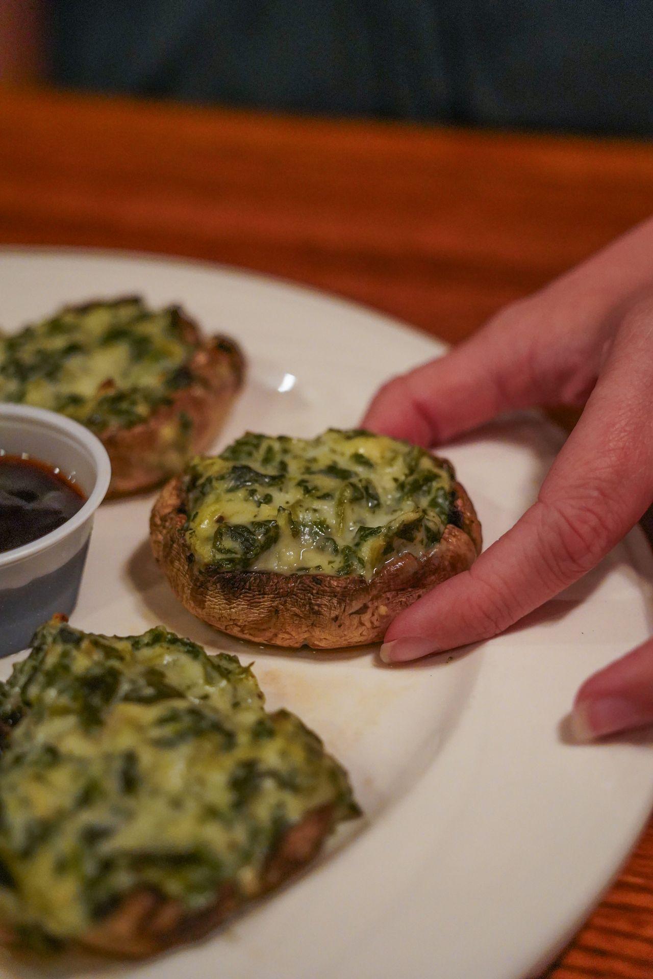A close up view of a hang picking up a spinach artichoke stuffed mushroom from P J Harrigan's in State College.