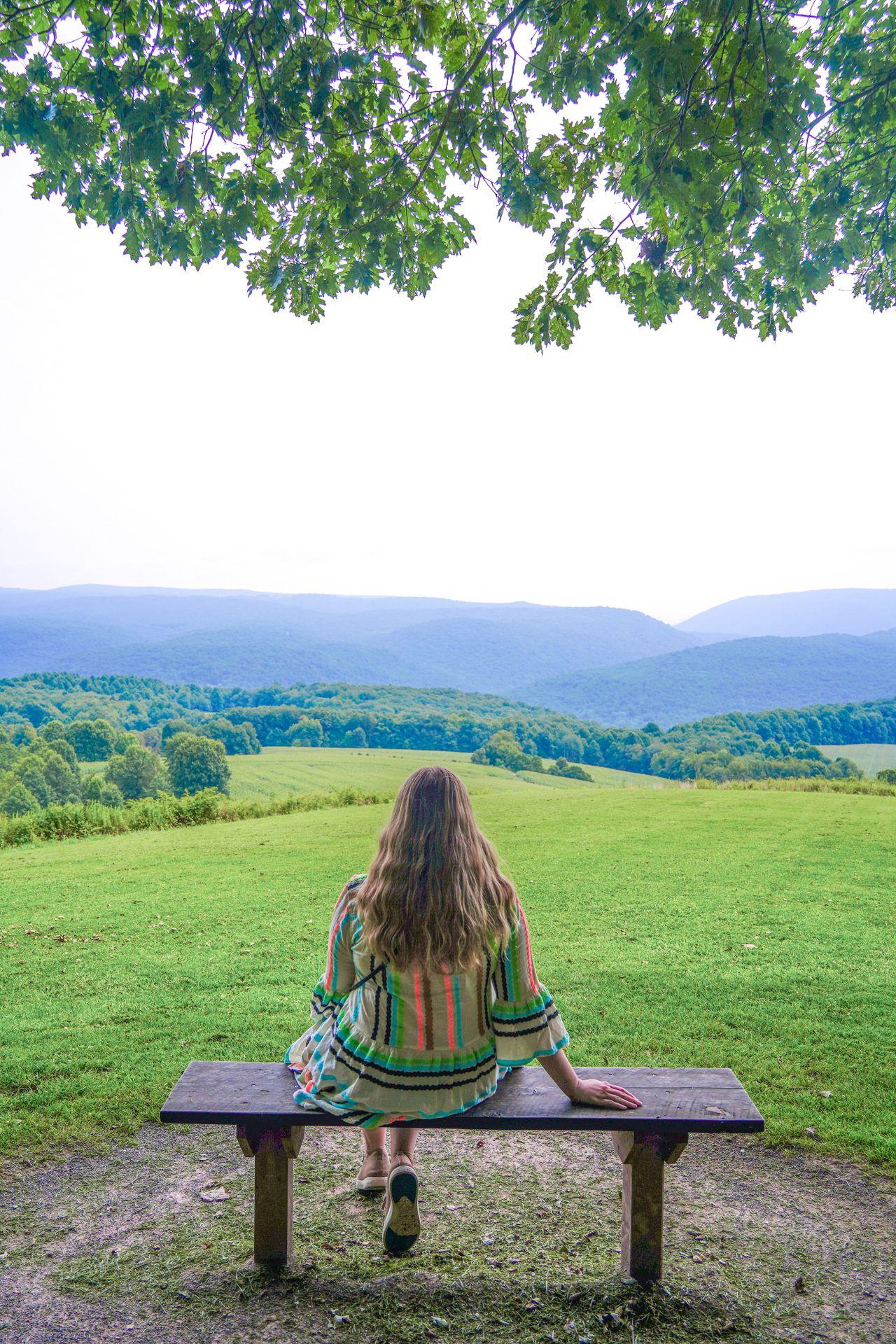 Lydia sitting on a bench and looking at the view at Kentuck Knob.