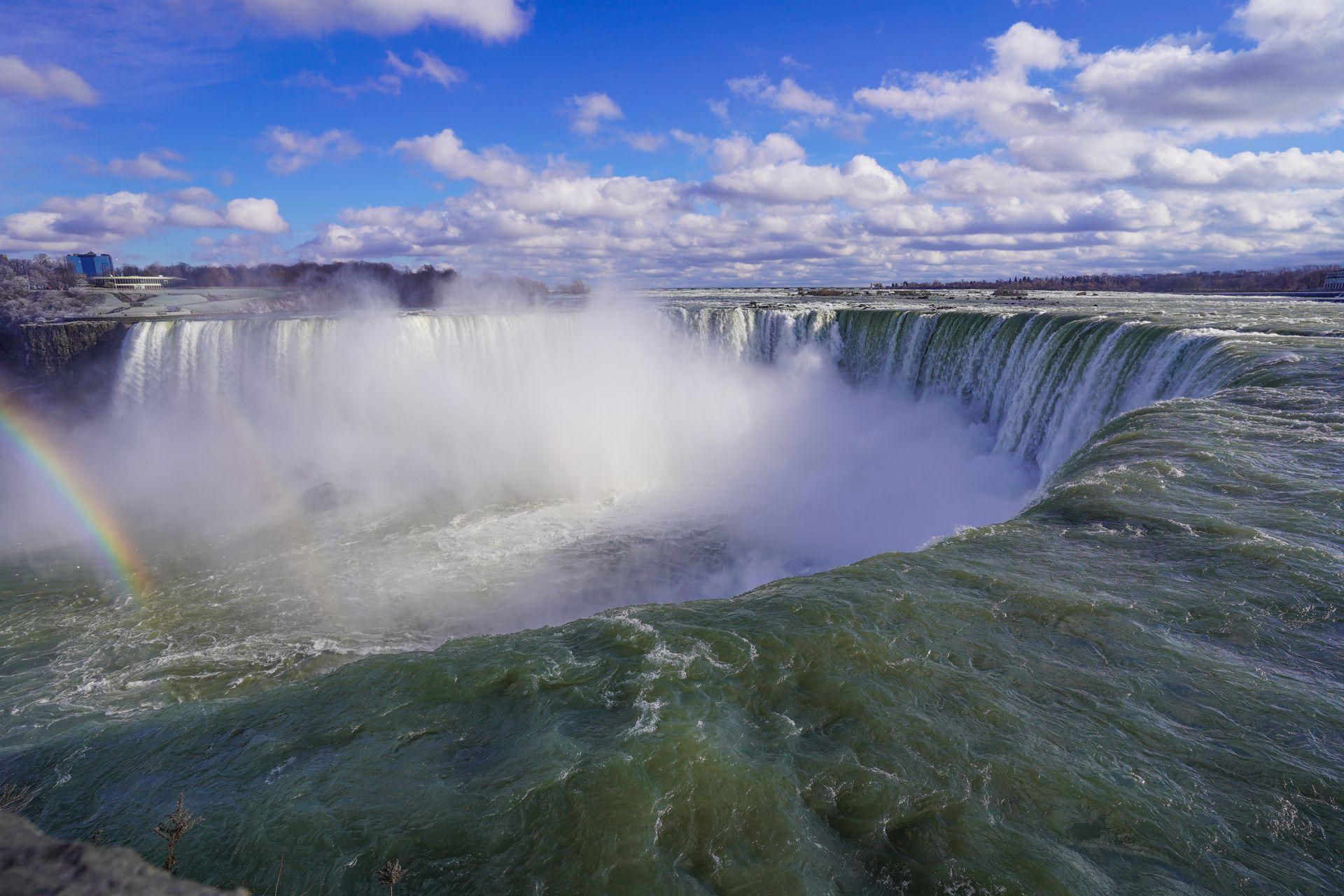 A view of Horseshoe Falls from Canada. There is a rainbow on the left side of the photo.