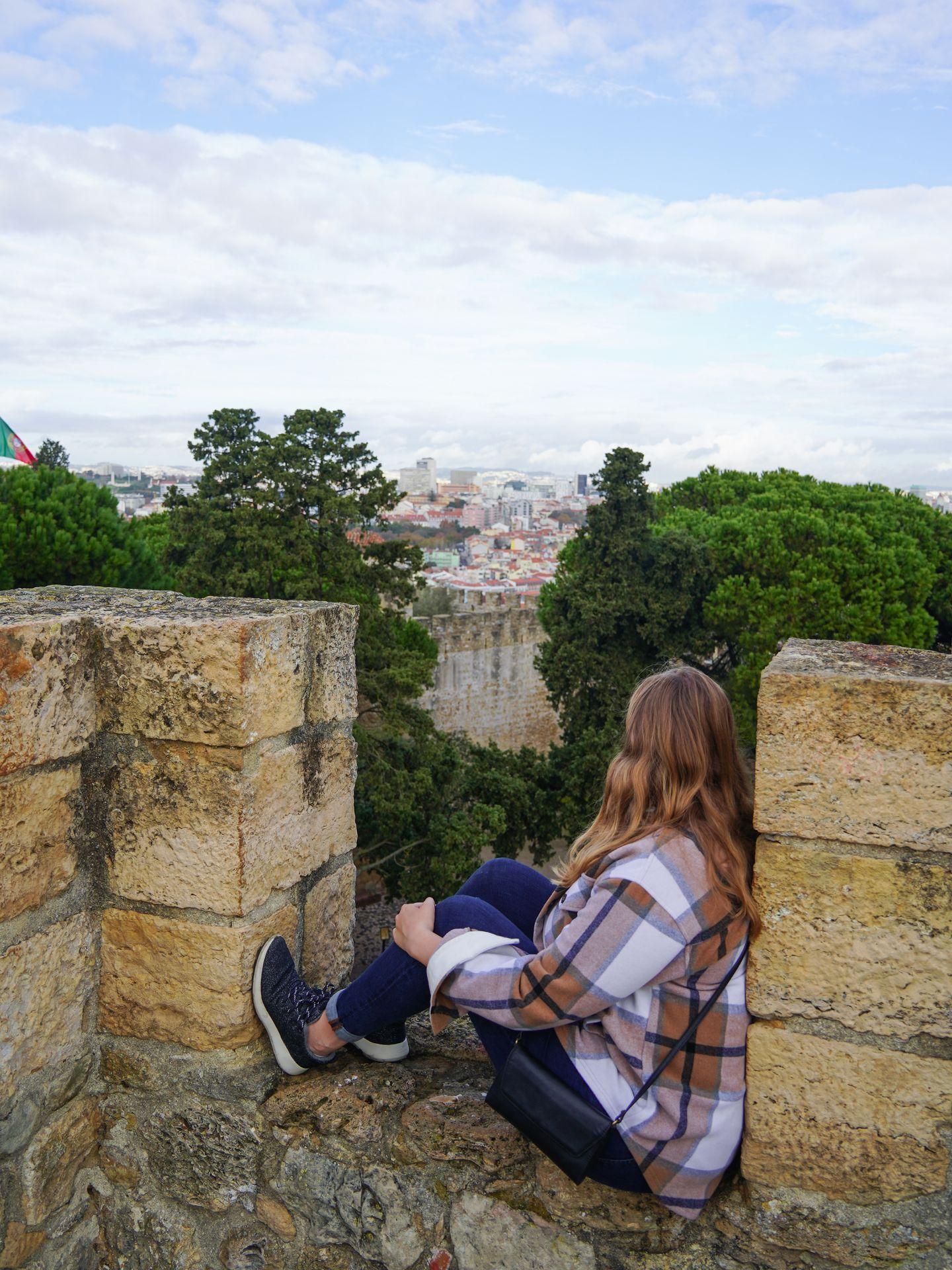 Lydia sitting on the castle walls at Castelo de S. Jorge